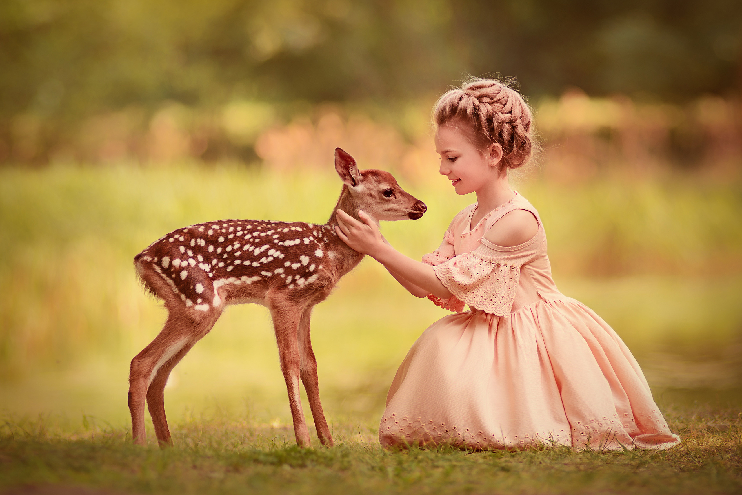 Девочка в розовом платье обнимает оленёнка бемби.