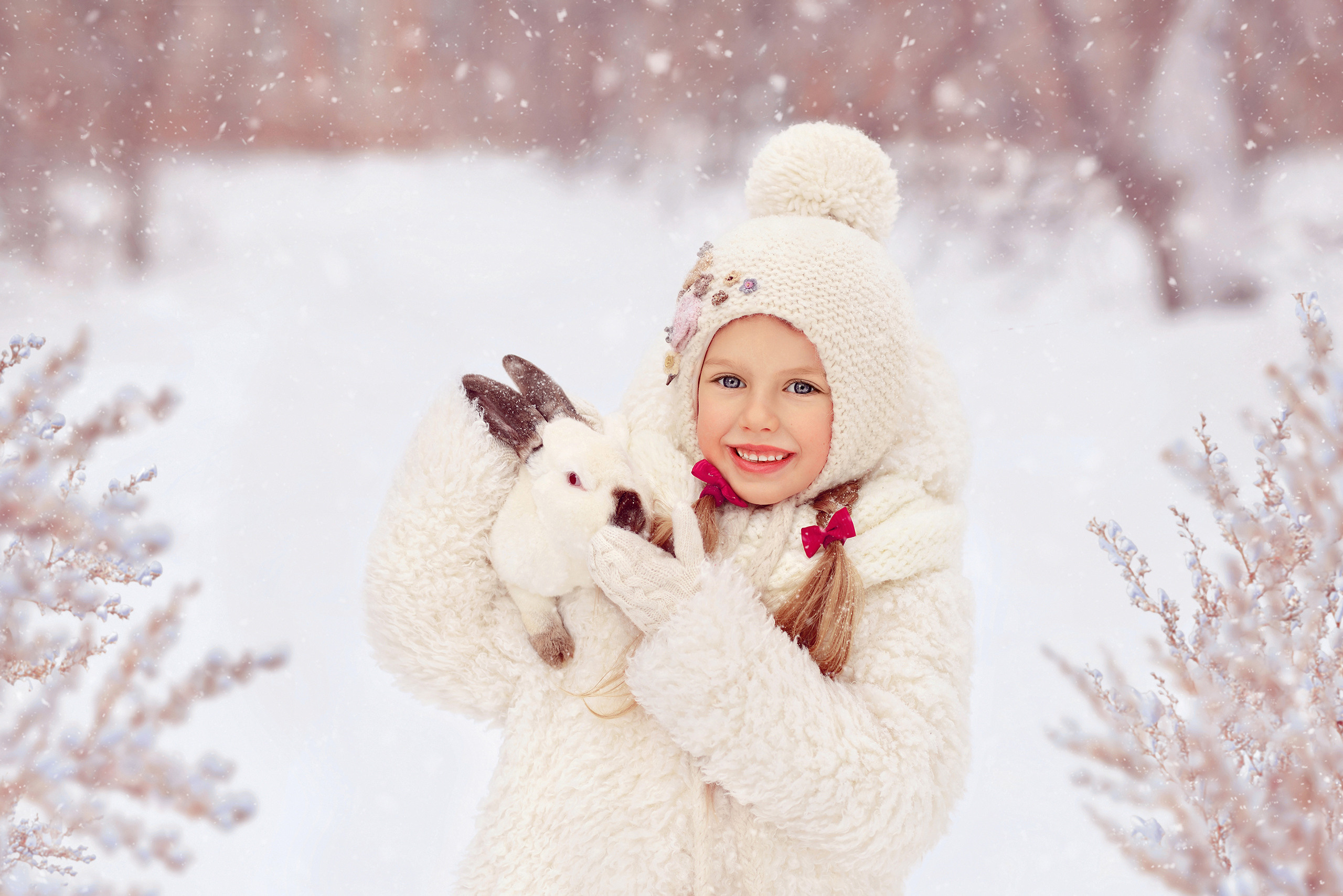Девочка в белой шубе и шапке держит на руках кролика.