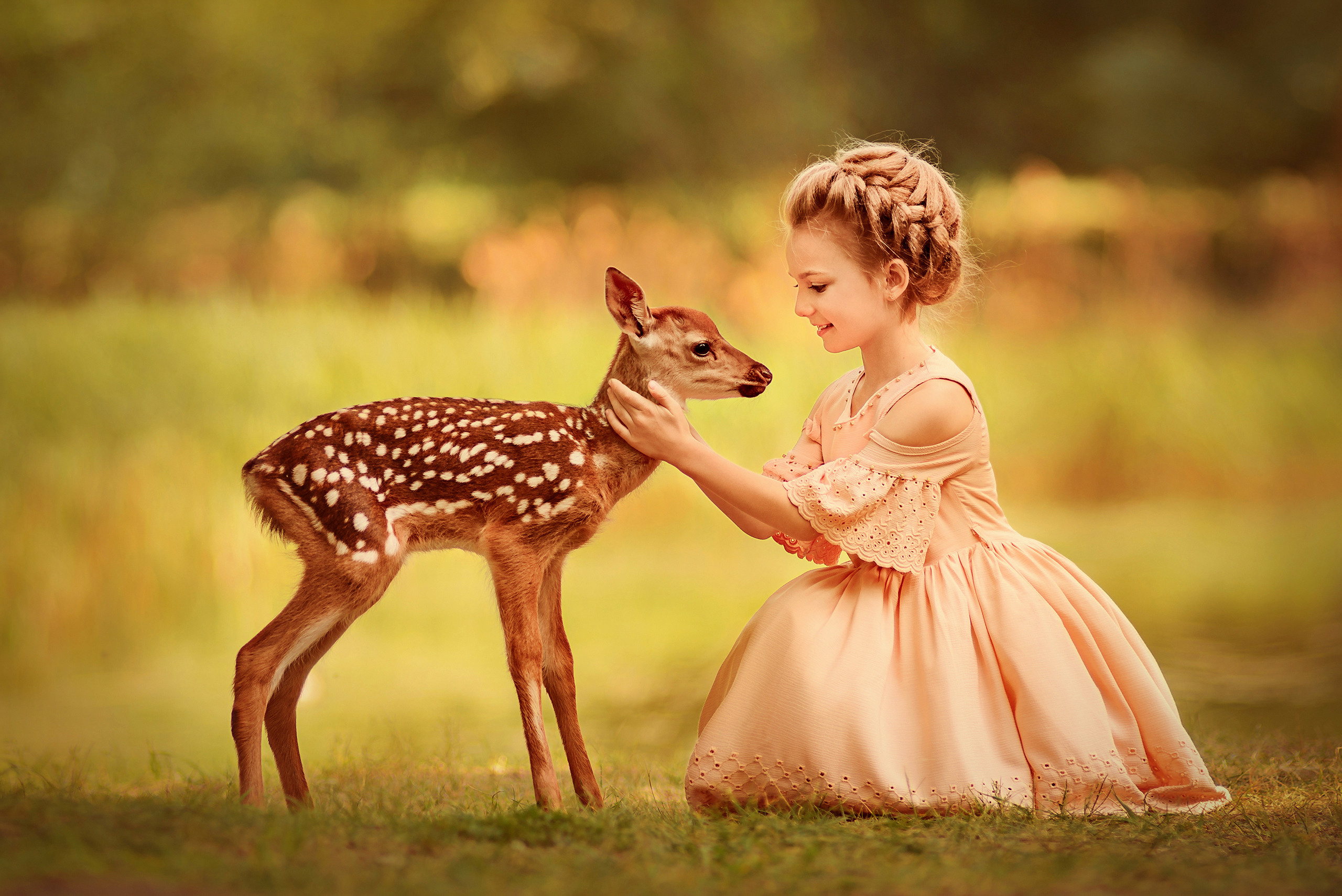 Девочка аккуратно гладит оленёнка.