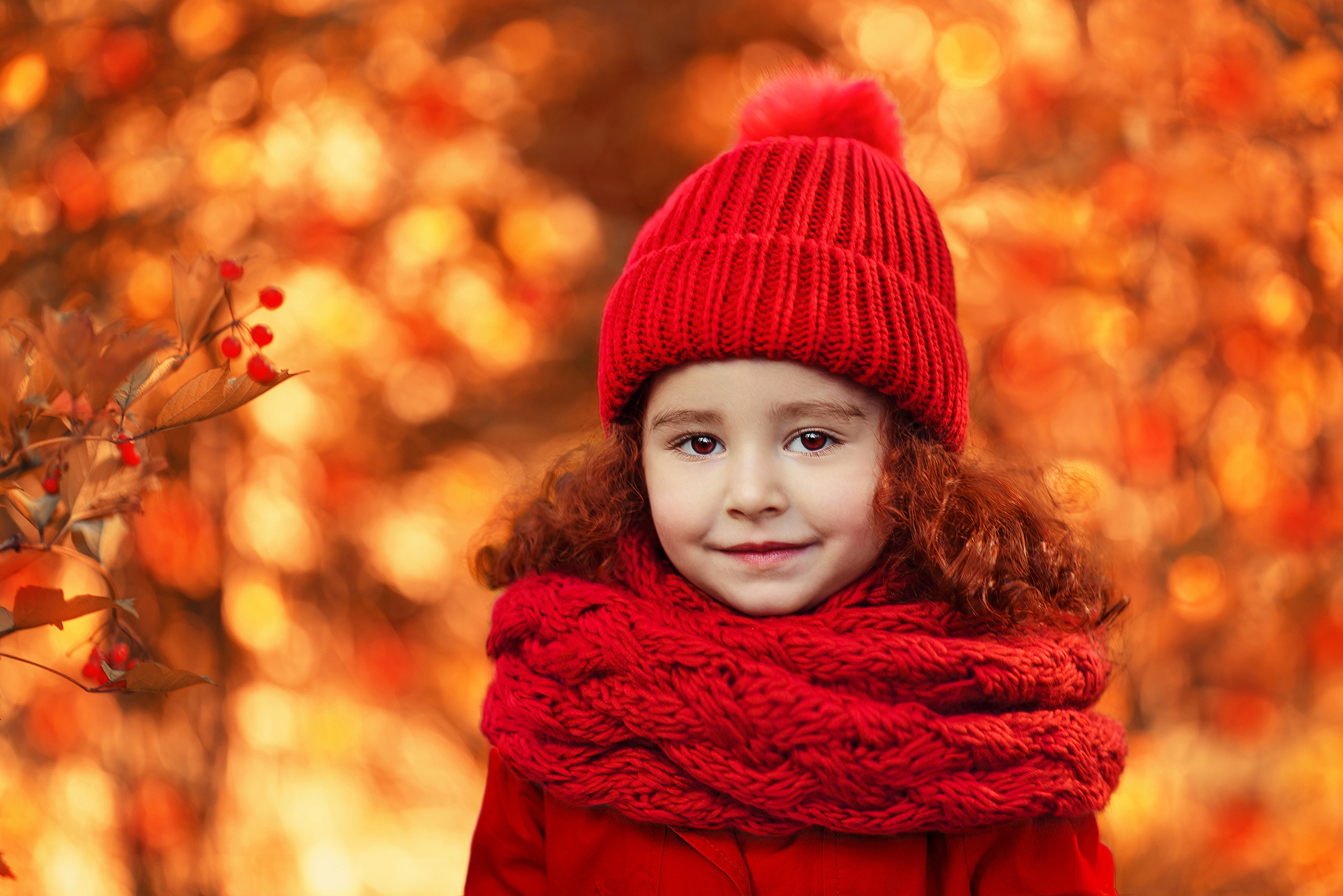 Портрет девочки в красном шарфе и шапке на фоне осеннего парка.
