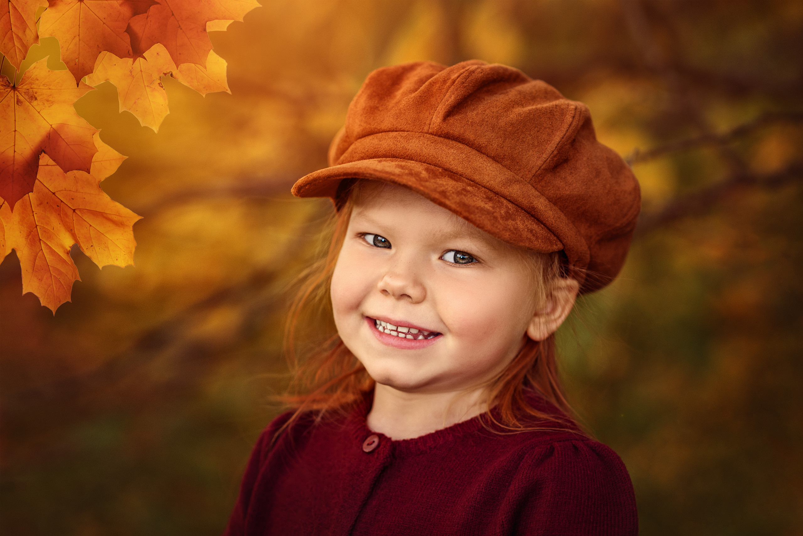 Рыжая девочка в кепке на фоне осеннего пейзажа.