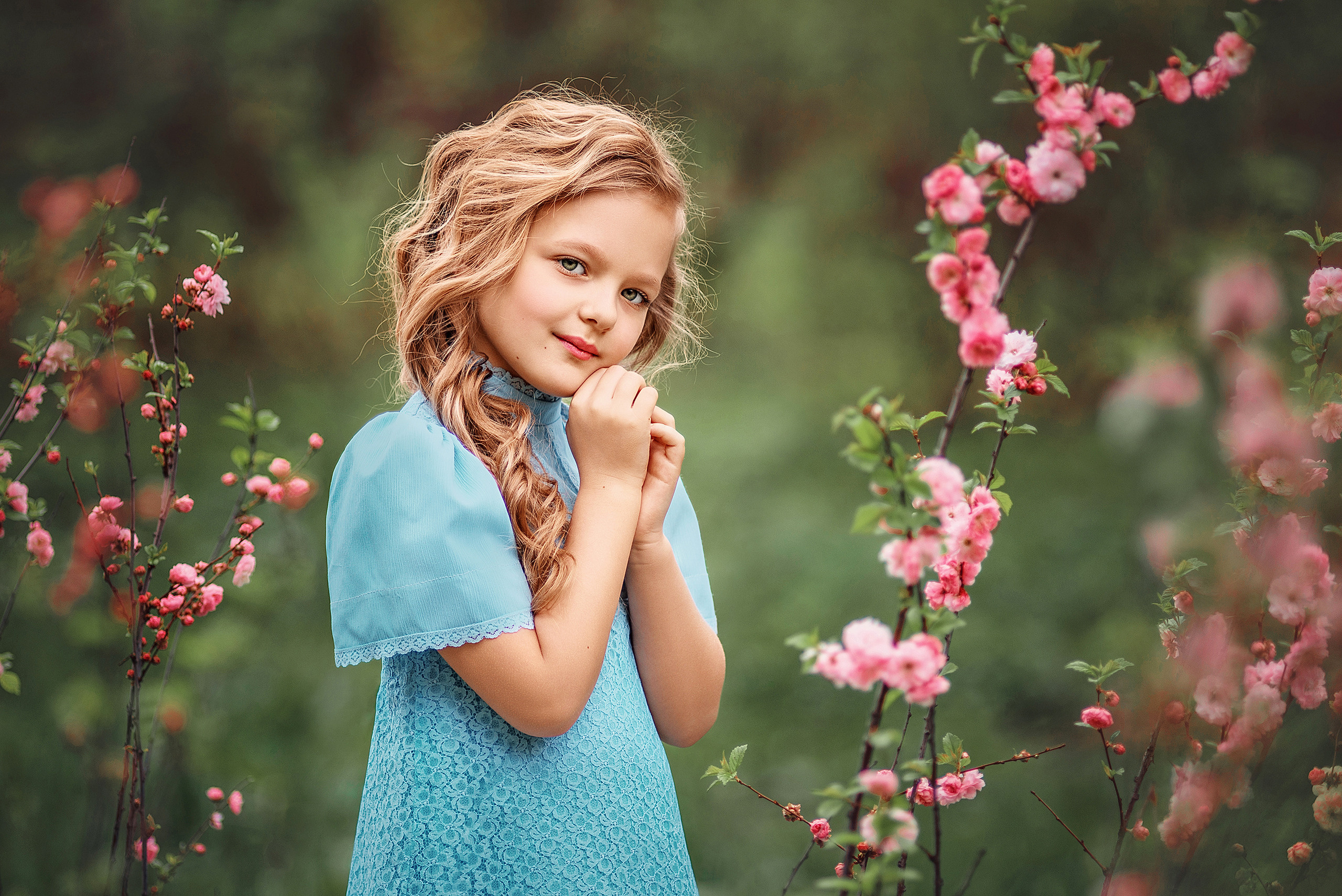 Девочка в голубом платье среди цветущего миндаля.
