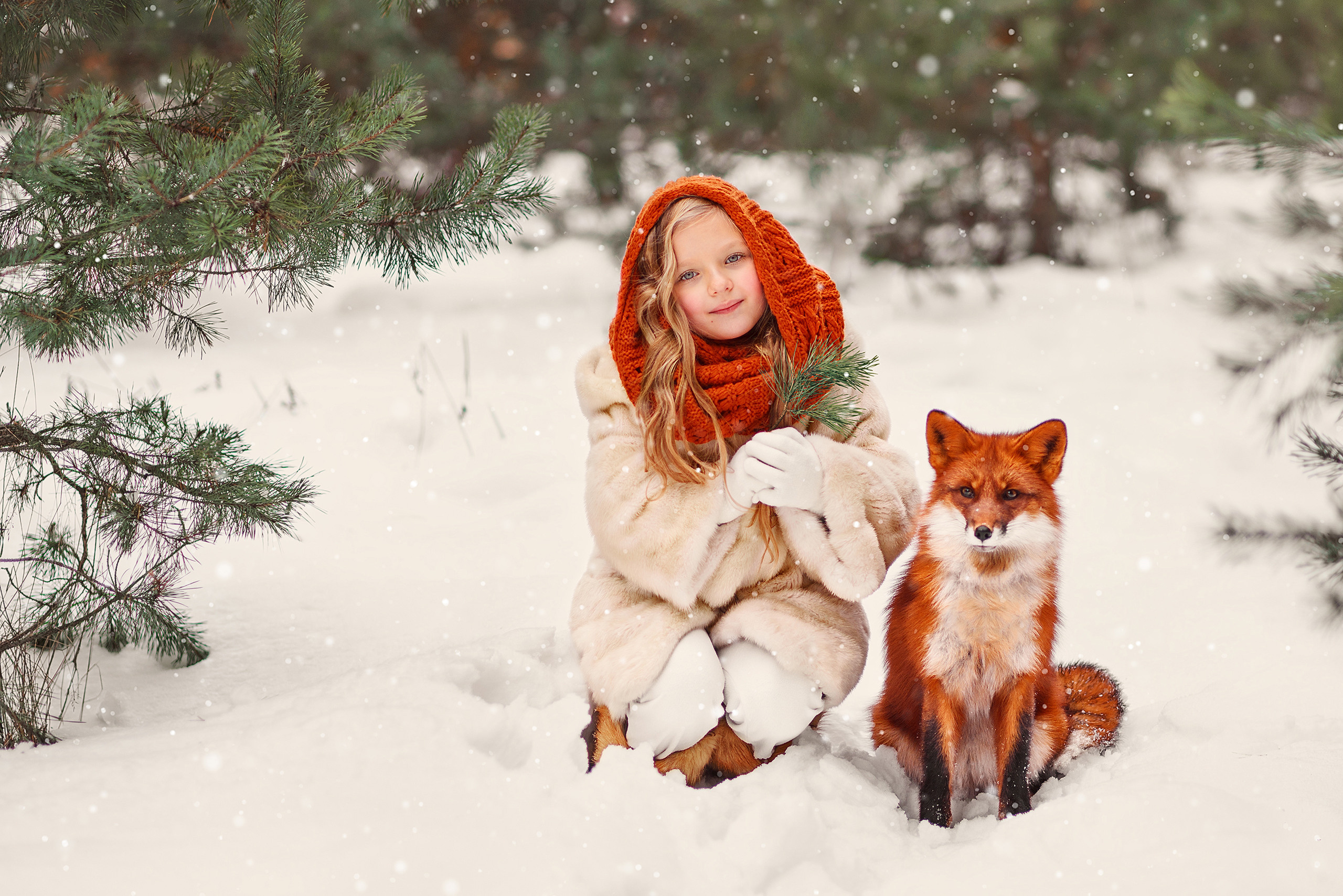 Девочка держит в руках еловую веточка, рядом с ней на снегу сидит лиса.