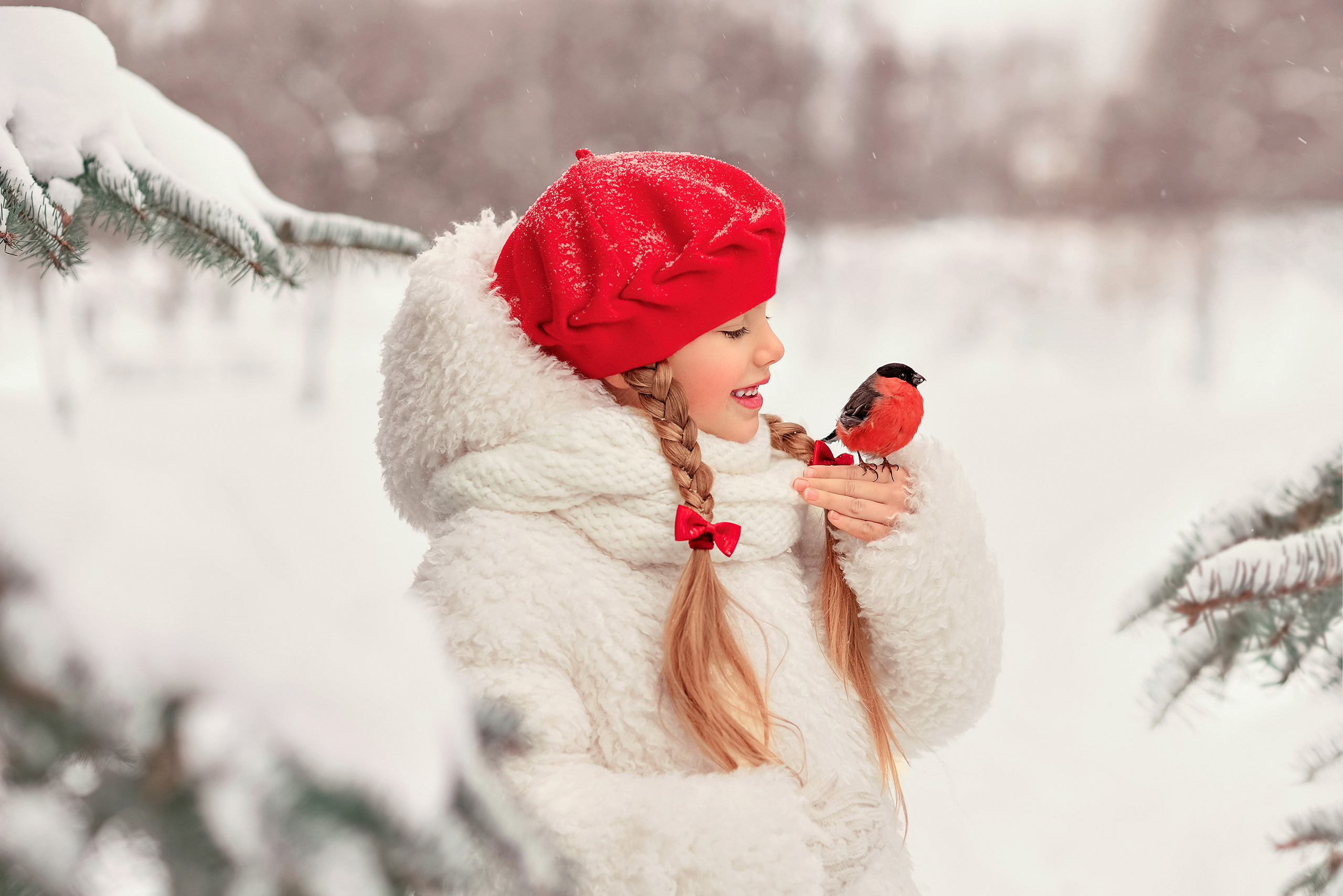 Девочка в красном берете и белой шубе держит на руке снегиря.