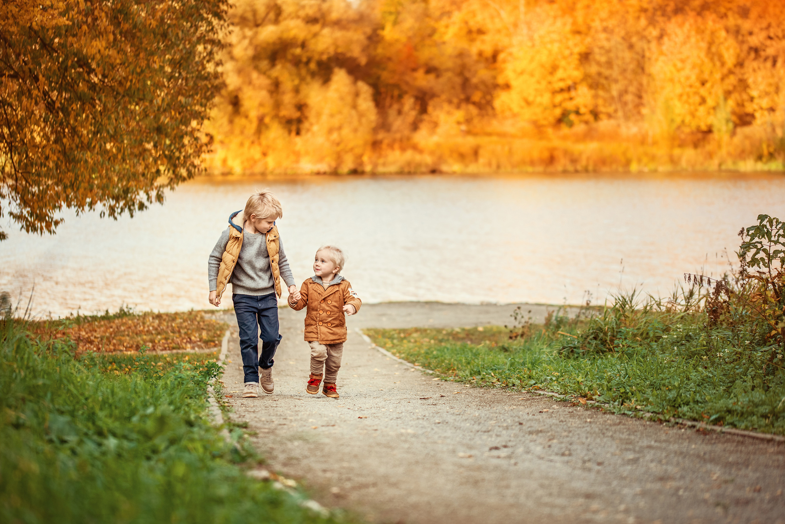 Два брата идут по дорожке в осеннем парке.