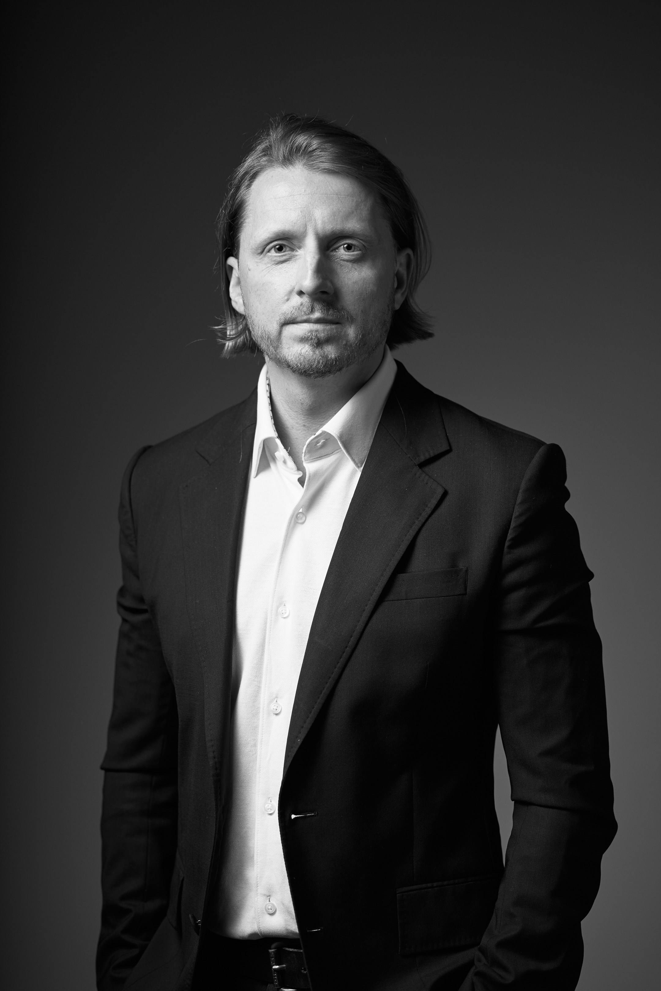 Black and white business portrait of a confident man in a suit on a dark studio background