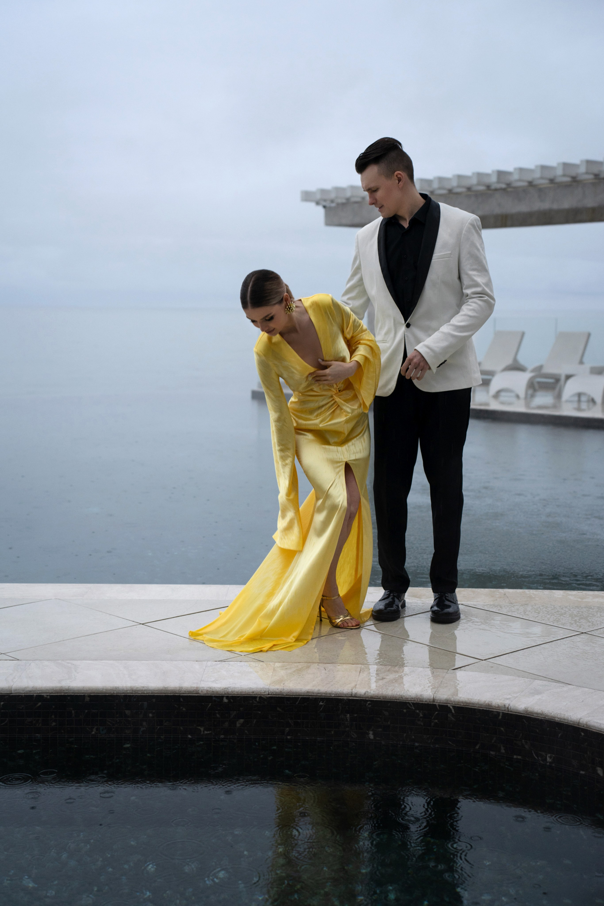 Мужчина и женщина в желтом платье стоят у бассейна. Свадебная фотосессия