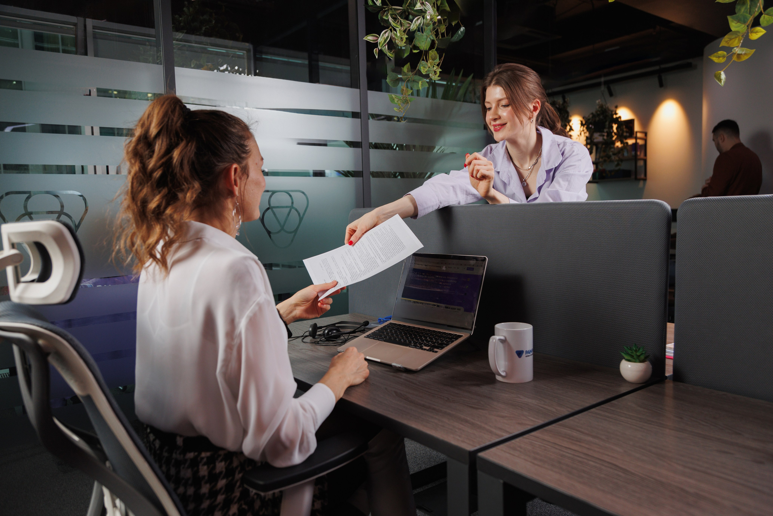 Момент взаимодействия в офисе: сотрудница передает документы коллеге. Фотограф Василий Жуков, Москва.