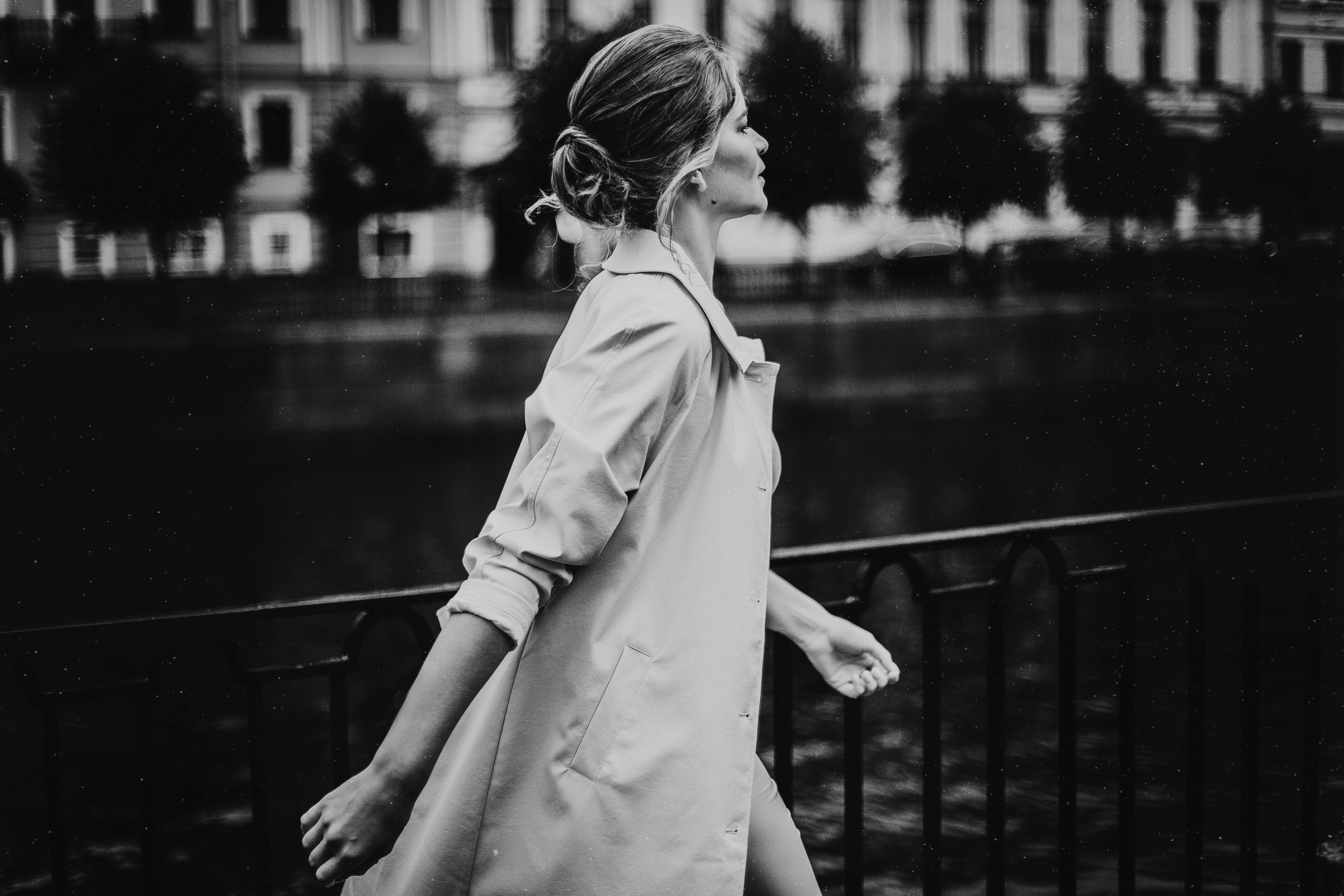 девушка в светлом плаще быстрым шагом идет по набережной