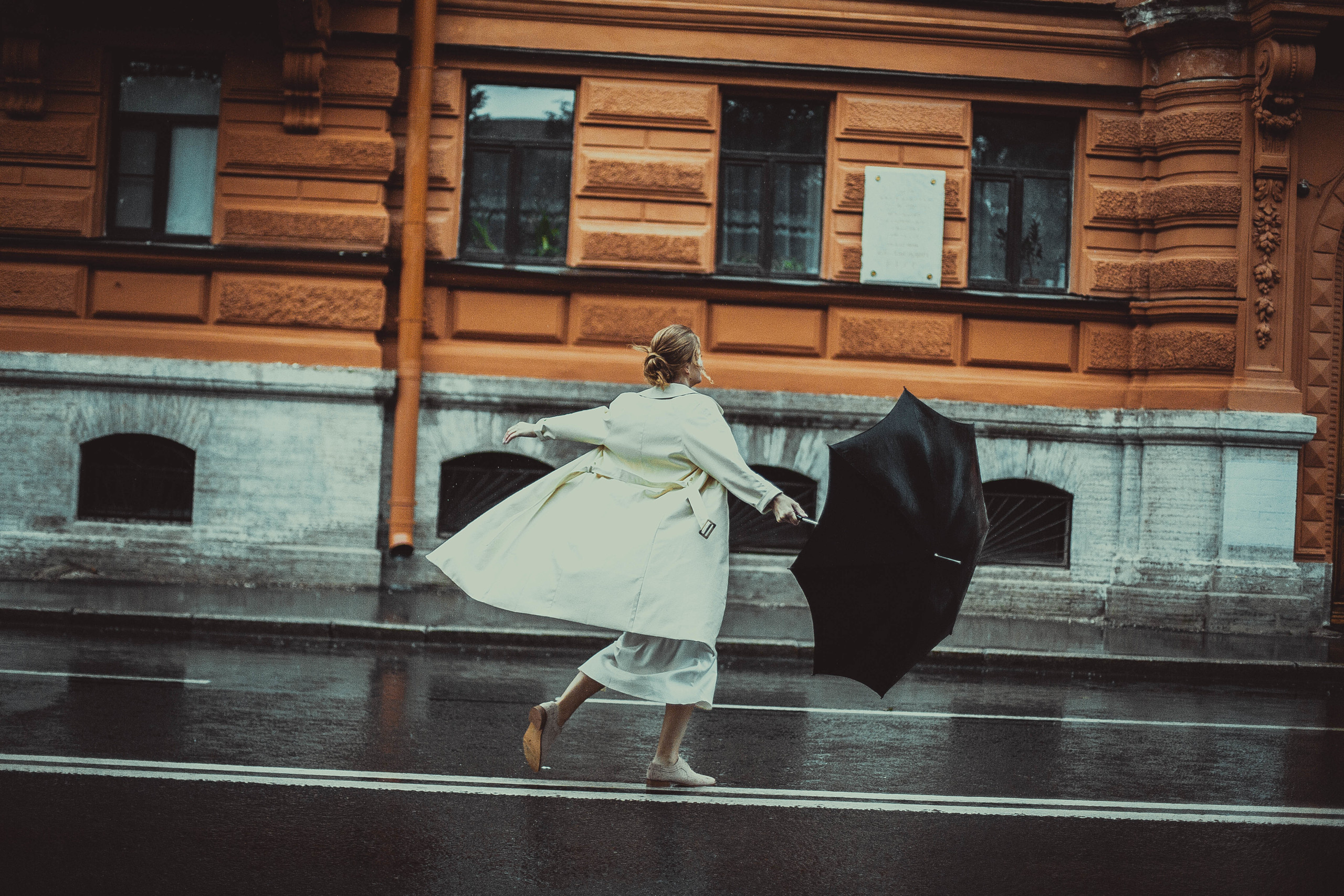 женщина с черным зонтом в белом плаще на двойной сплошной