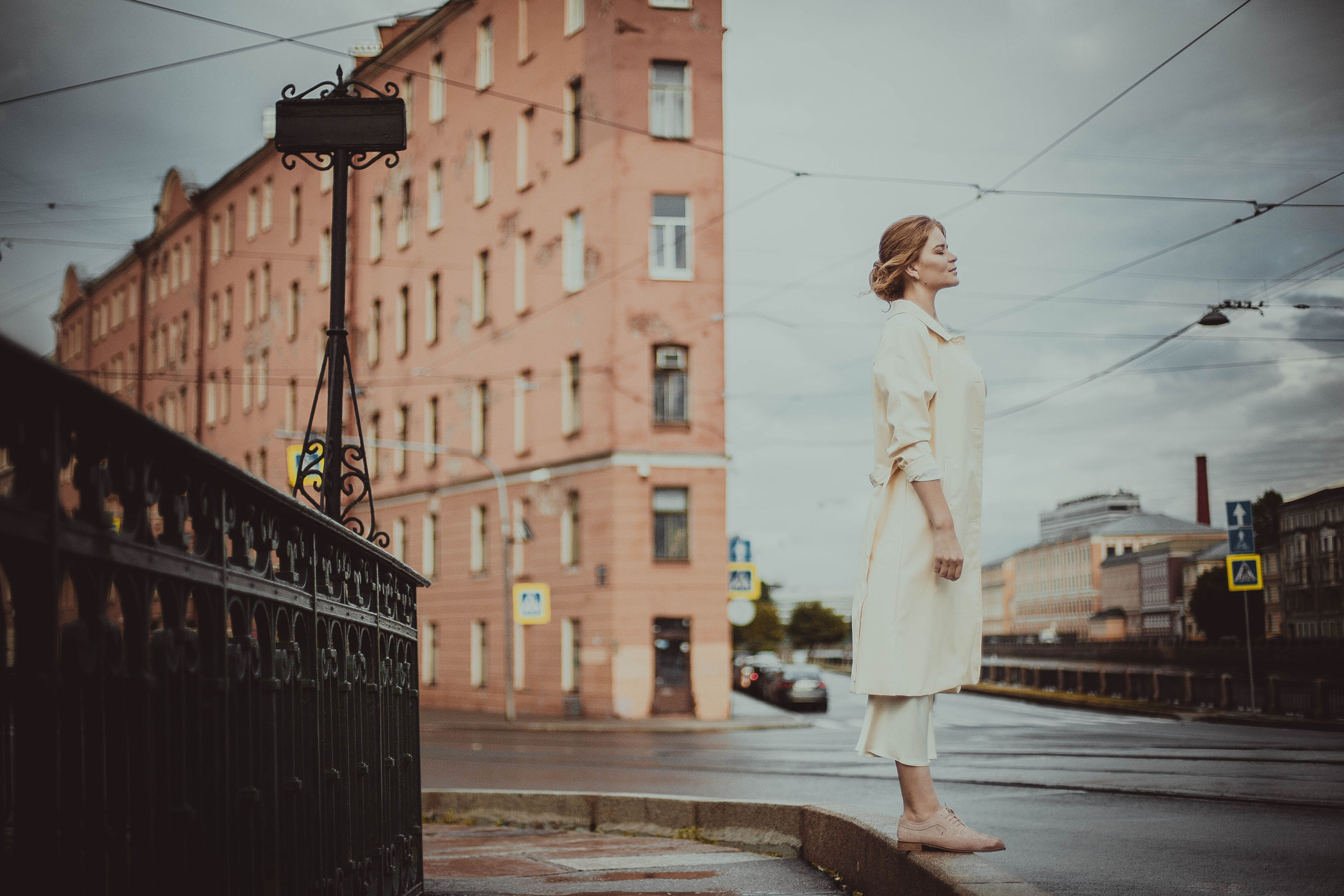 женщина в белом плаще на поребрике моста через канал Грибоедова