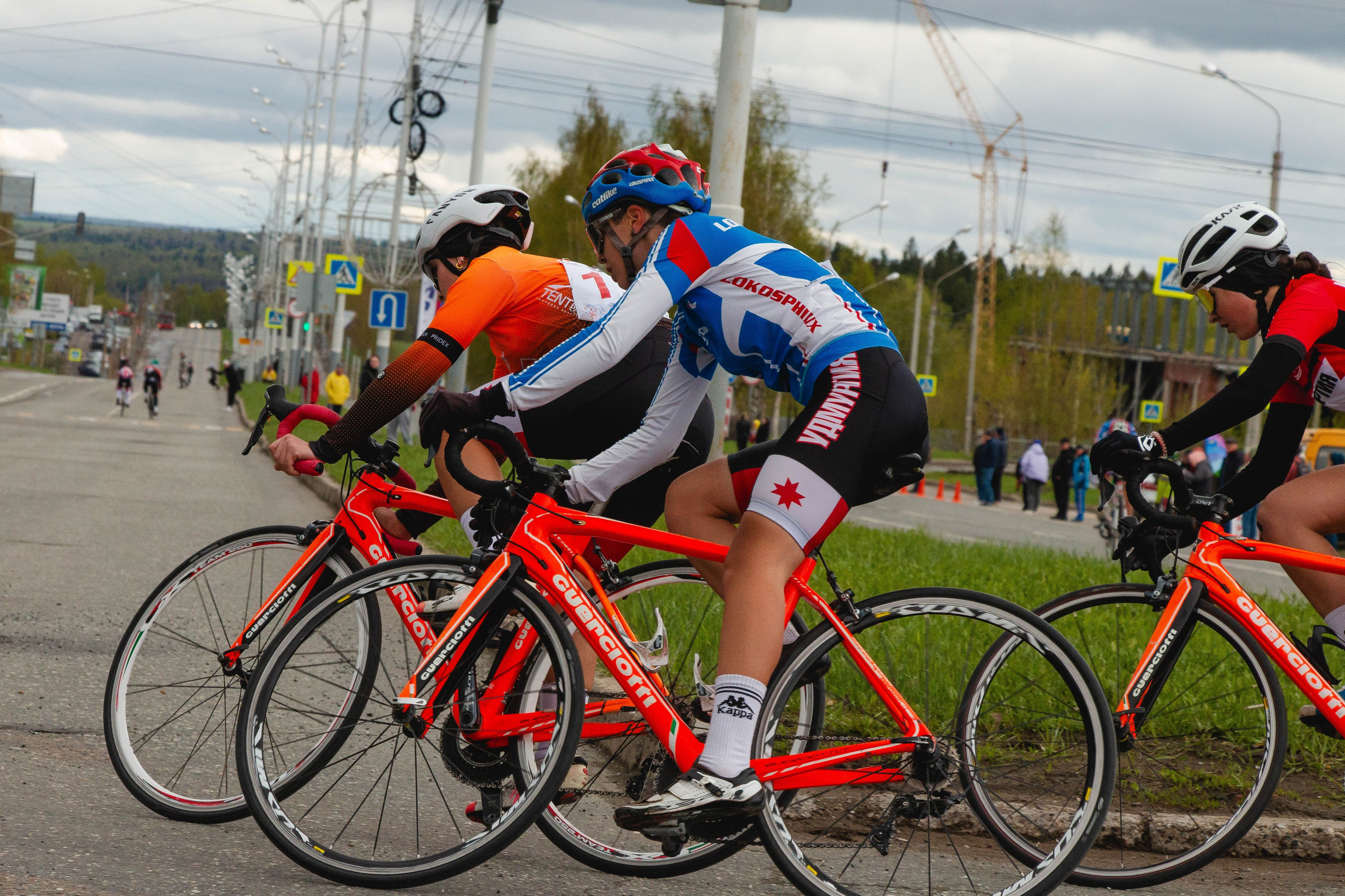 Группа велосипедистов входит с наклоном в крутой поворот