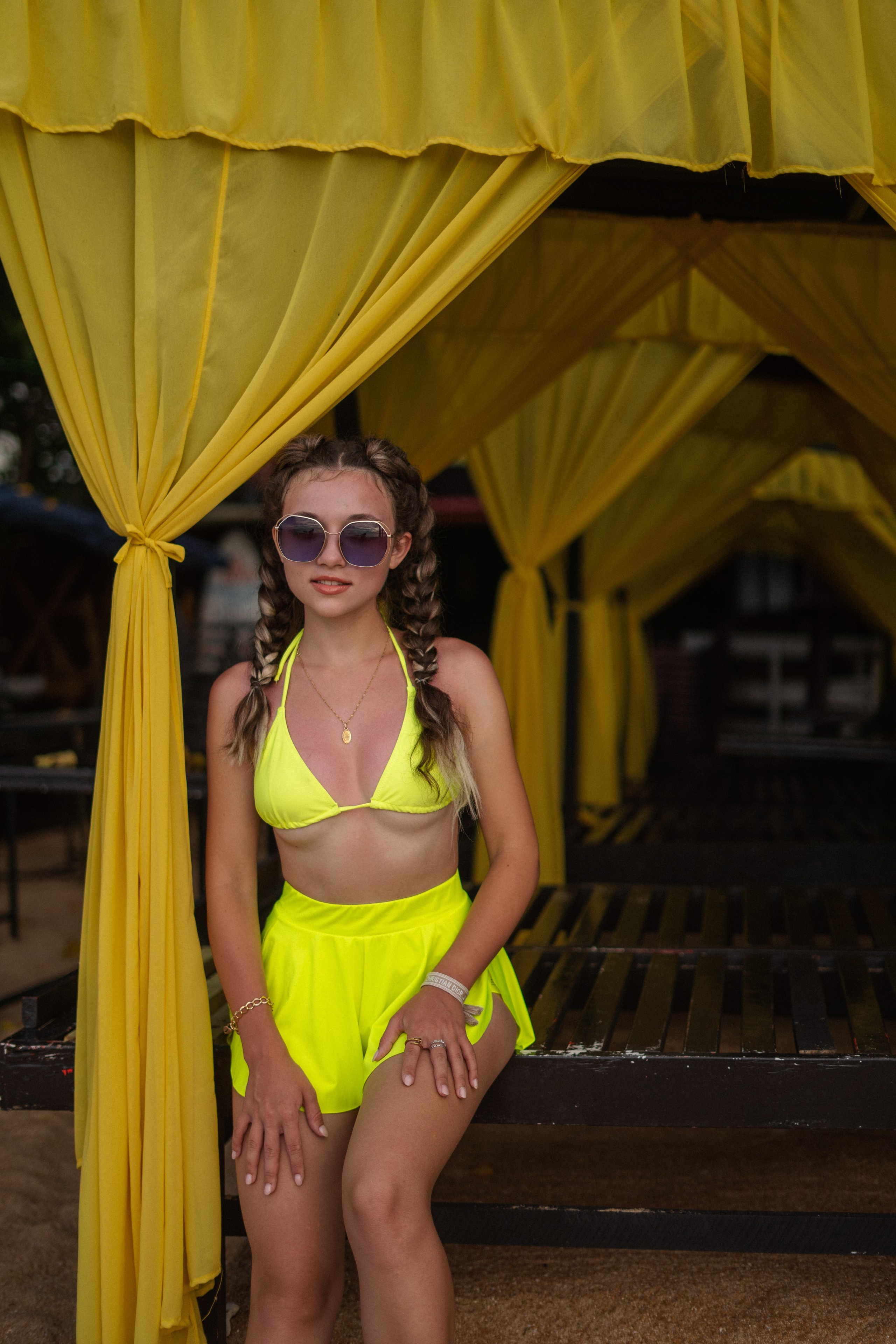 a girl with braids in a yellow swimsuit by the water during a photoshoot