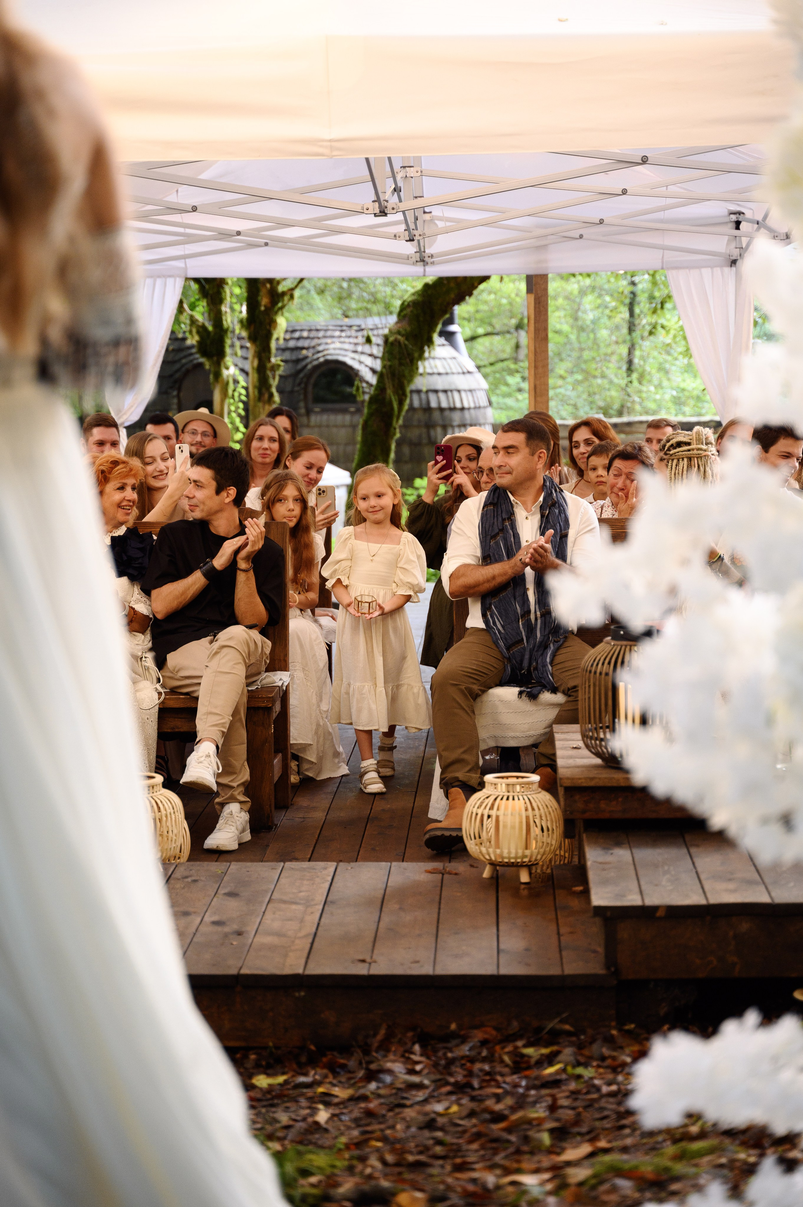 Гости сидят идёт церемония бракосочетания и маленькая девочка среди гостей несёт кольца молодым