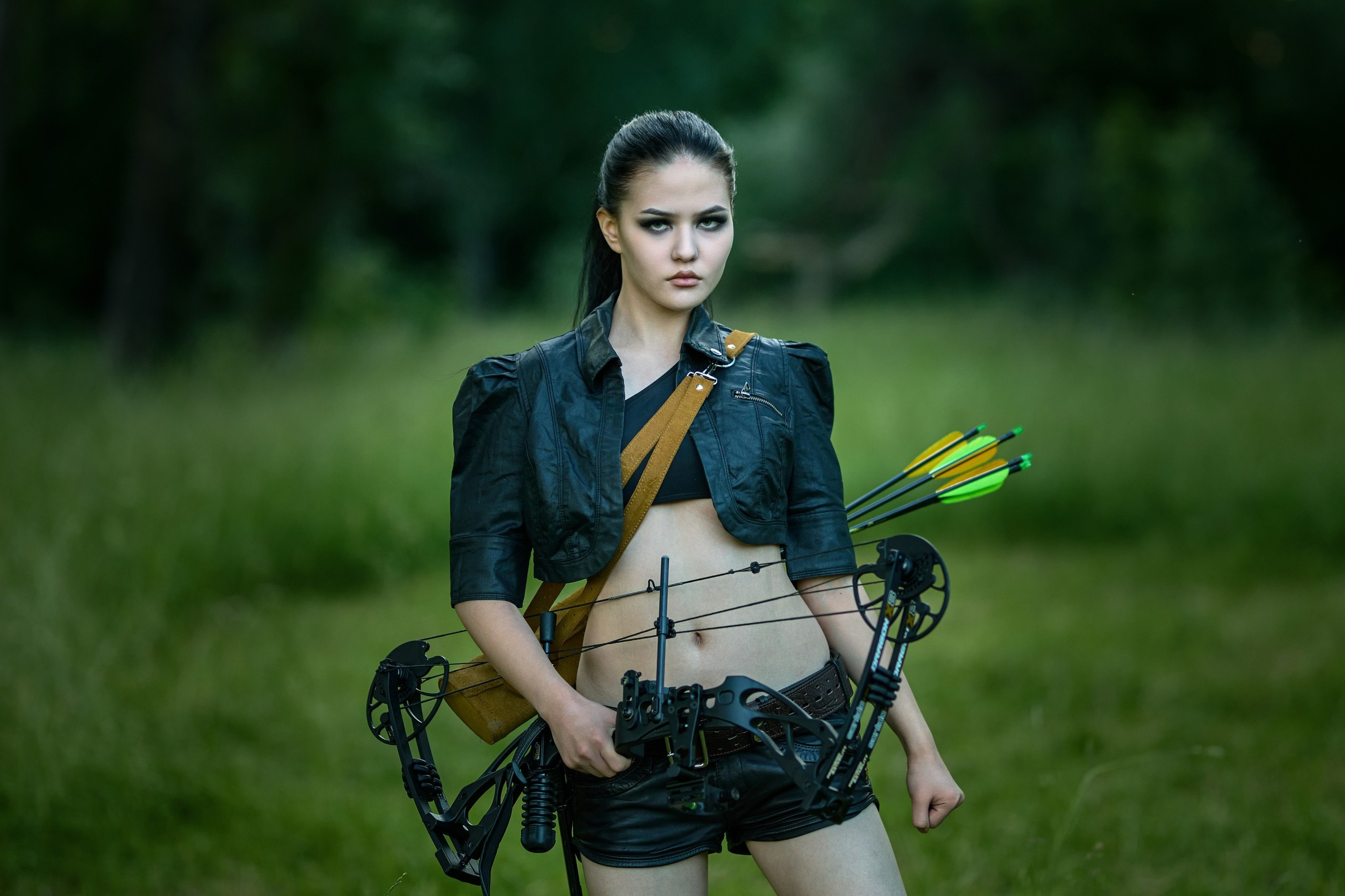 Девушка в кожаной одежде с луком и стрелами идет по дереву