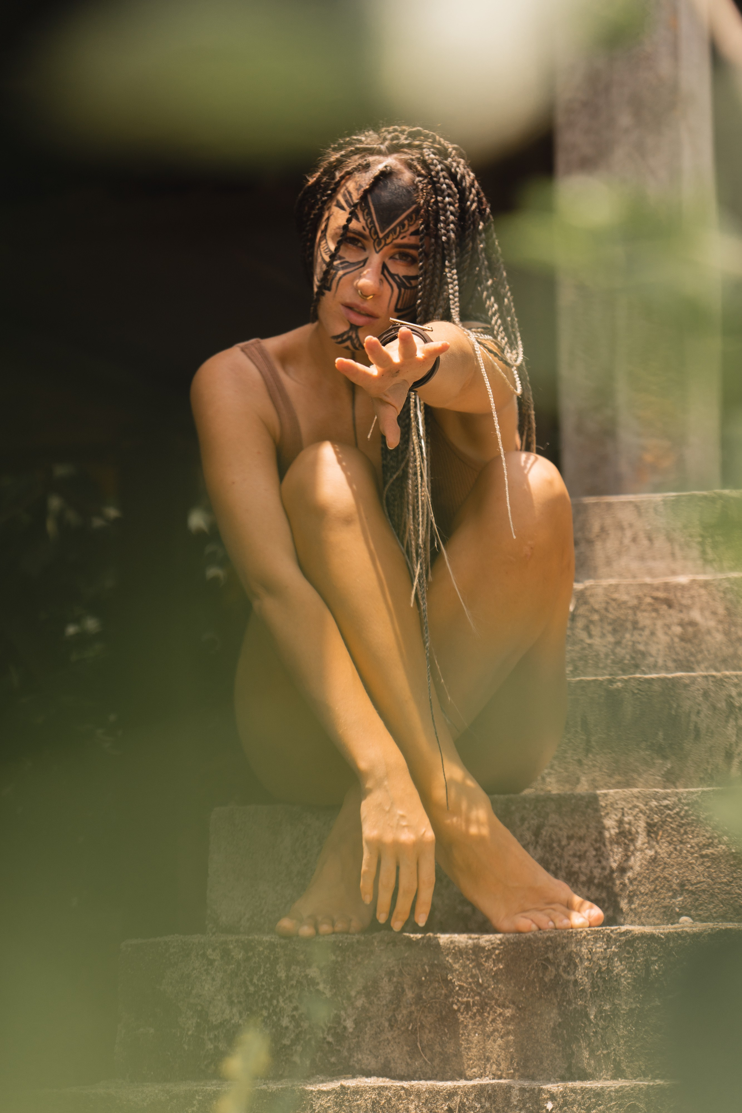 a girl with braids and face paint walking in the jungle