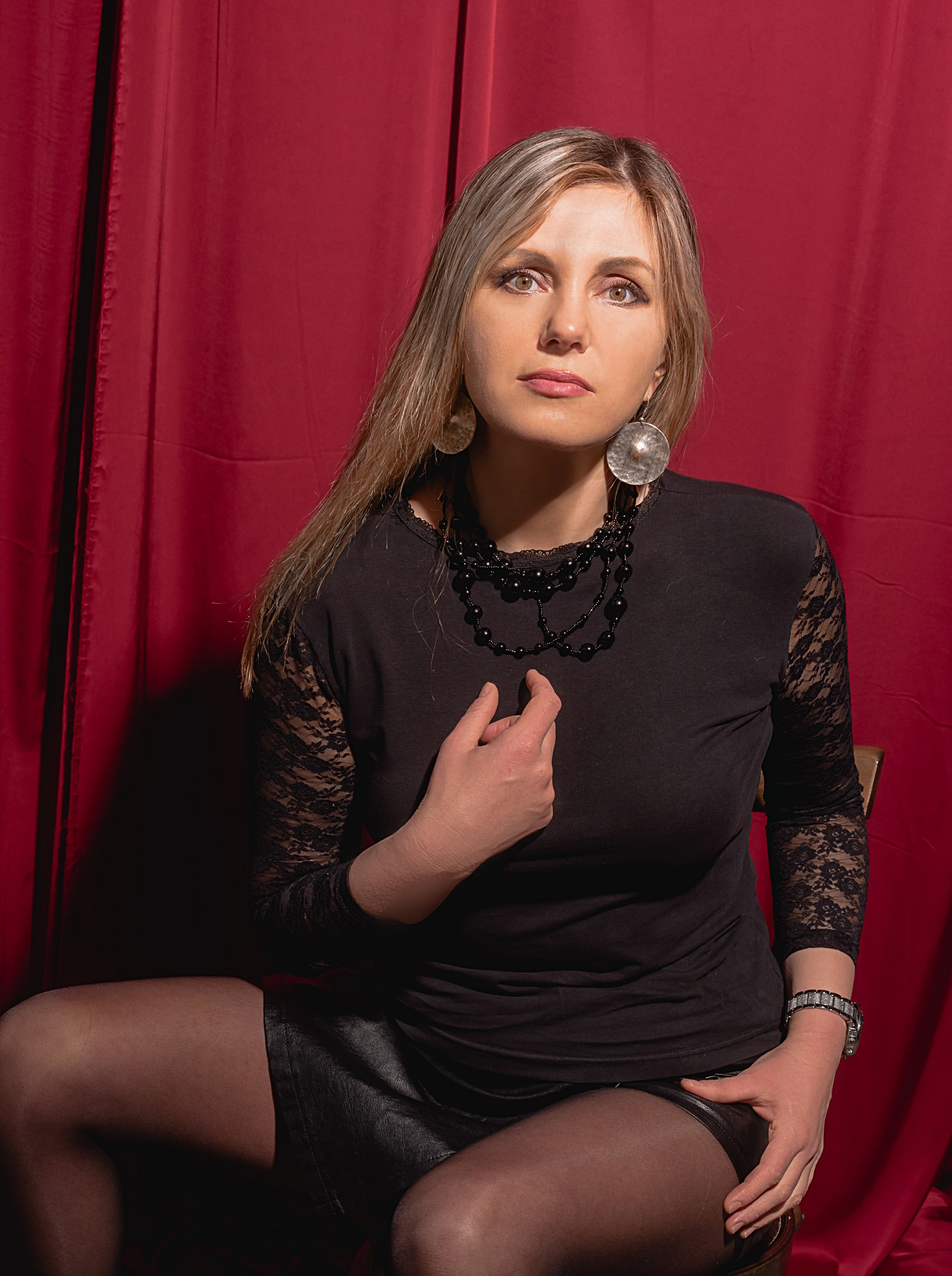 Фотография девушки на красном фоне сидит.