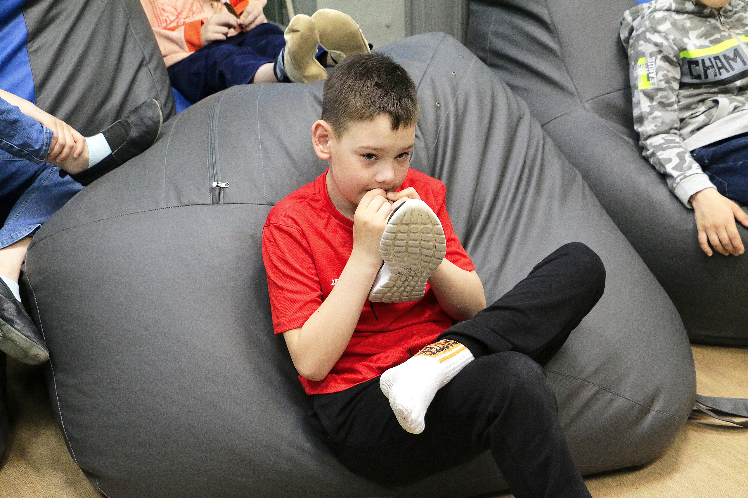 Шнурки на кроссовках запутались. Узел на кроссовках. Мальчик в кресле сидит, и зубами распутывает узел на своих кроссовках. 