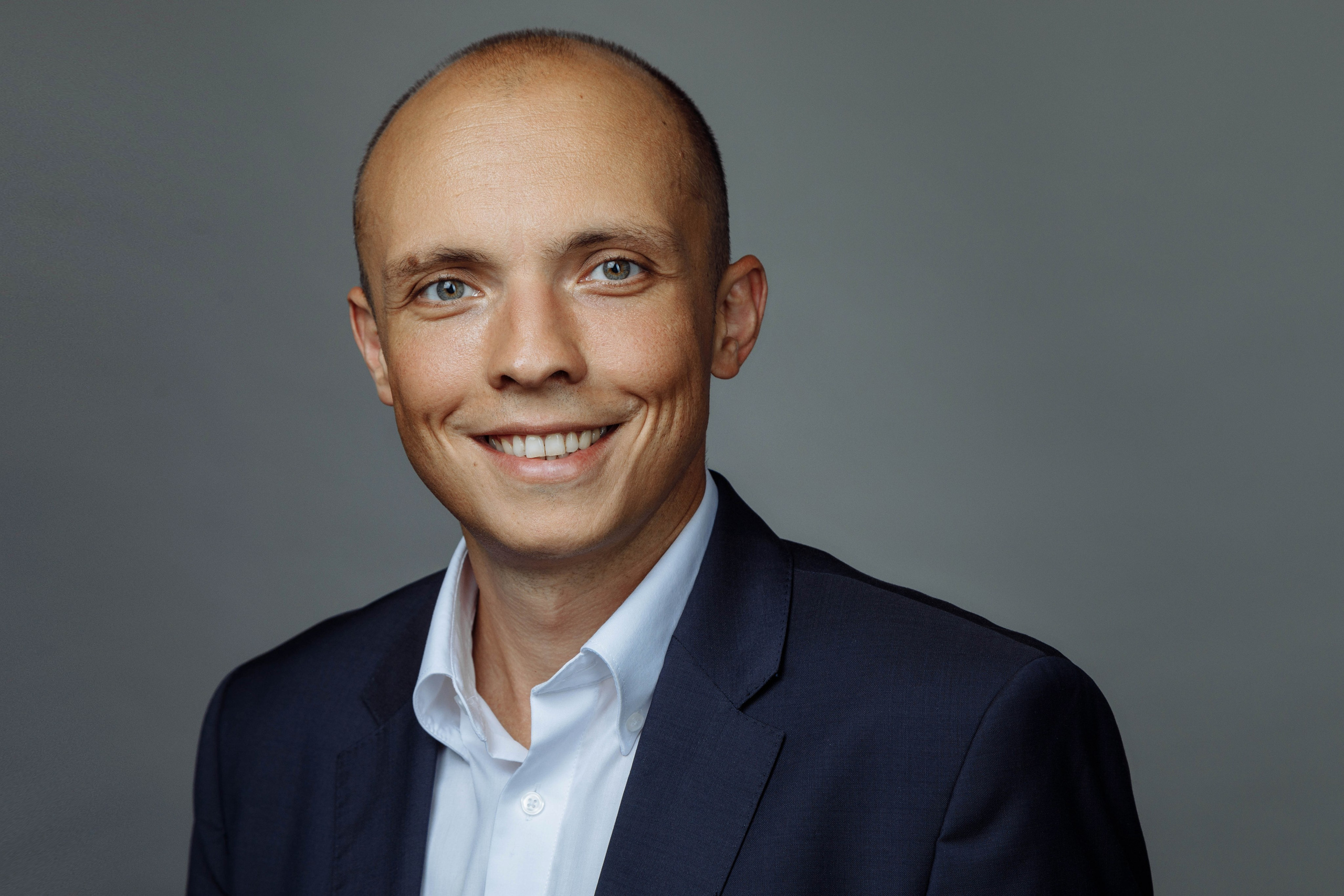 Дружелюбный деловой портрет улыбающегося мужчины на однотонном фоне.