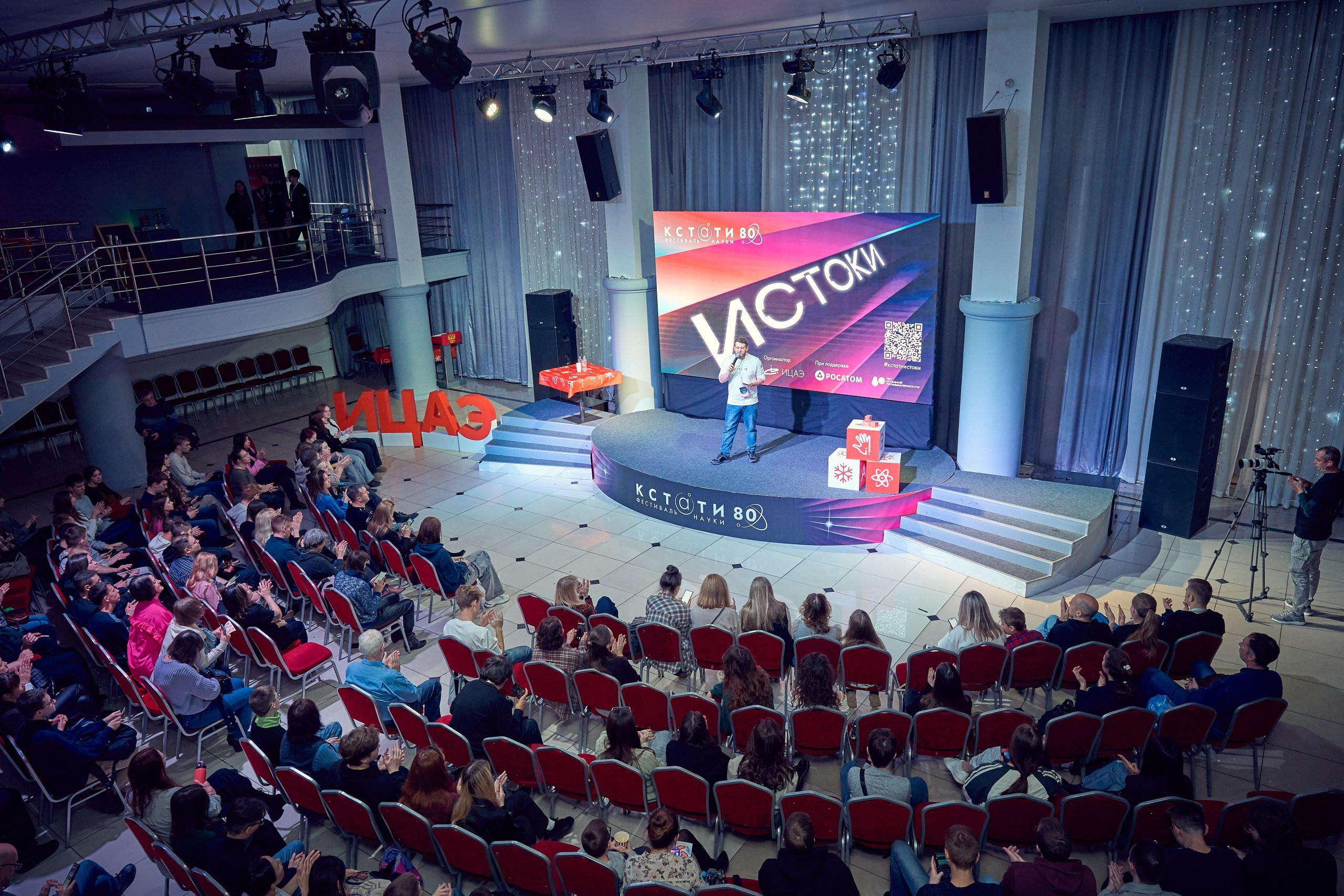 общий план зала где видны сцена и рассадка людей полукругом