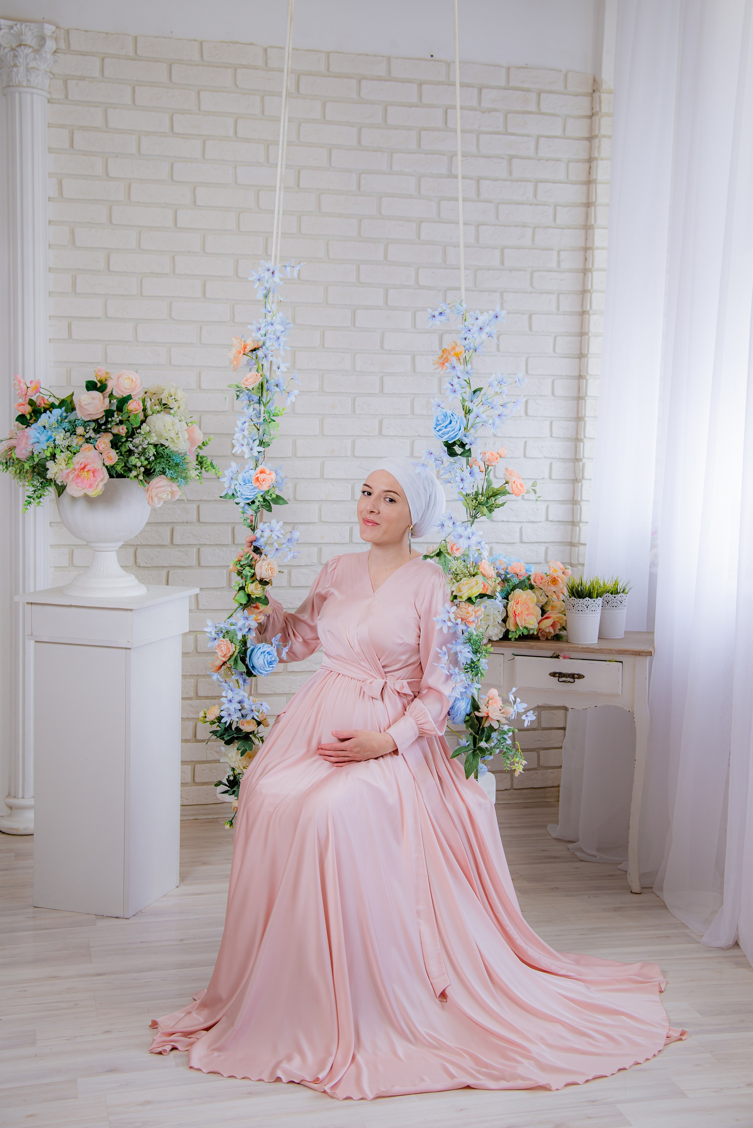 Фотосессия беременных в фотостудии в Уфе: будущая мама в элегантном платье из проката, с профессиональным макияжем и прической. Она счастливо позирует на фоне стильного интерьера, отражая красоту и нежность материнства.