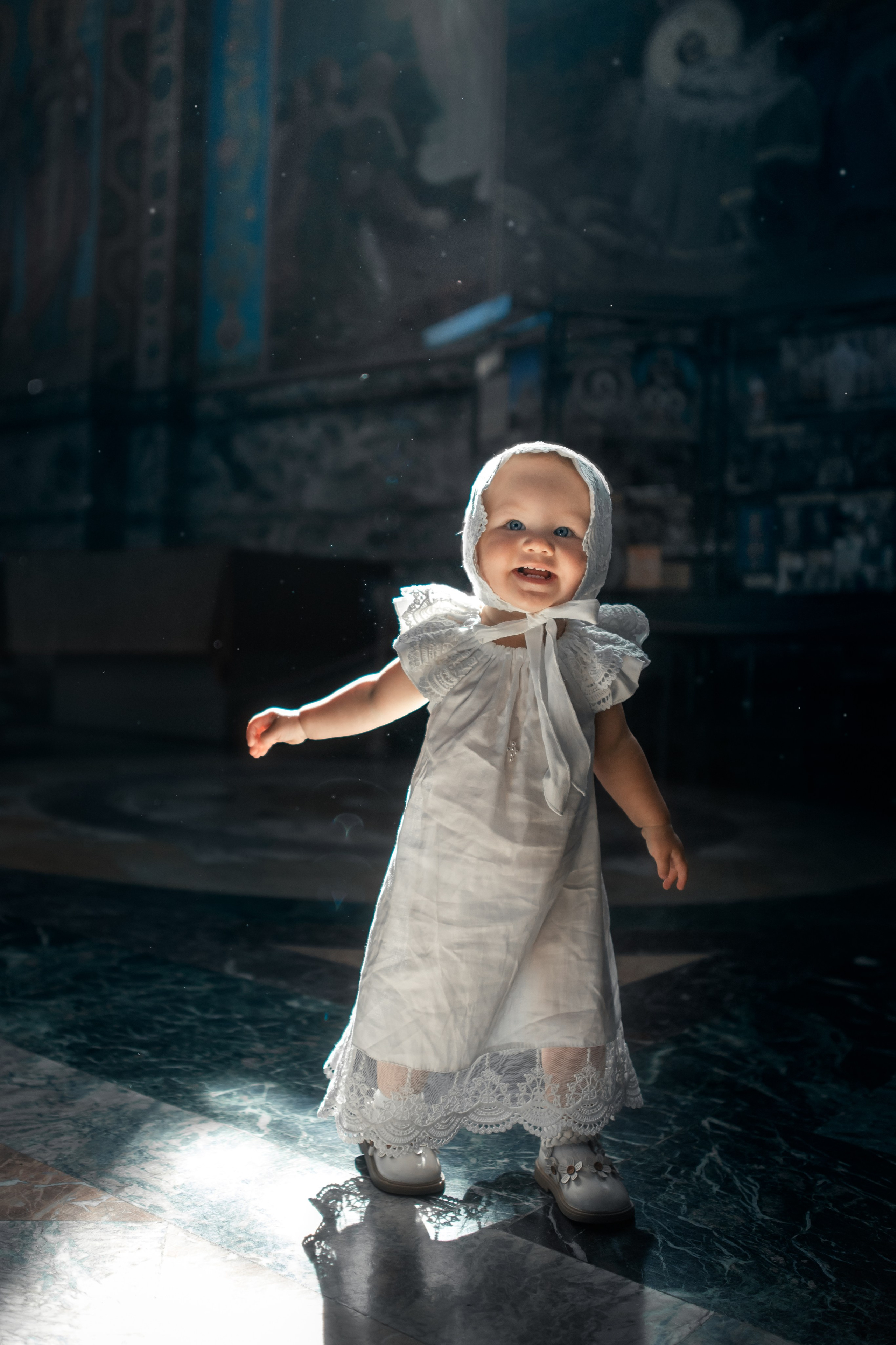 малышка в крестильном платье в солнечном свете