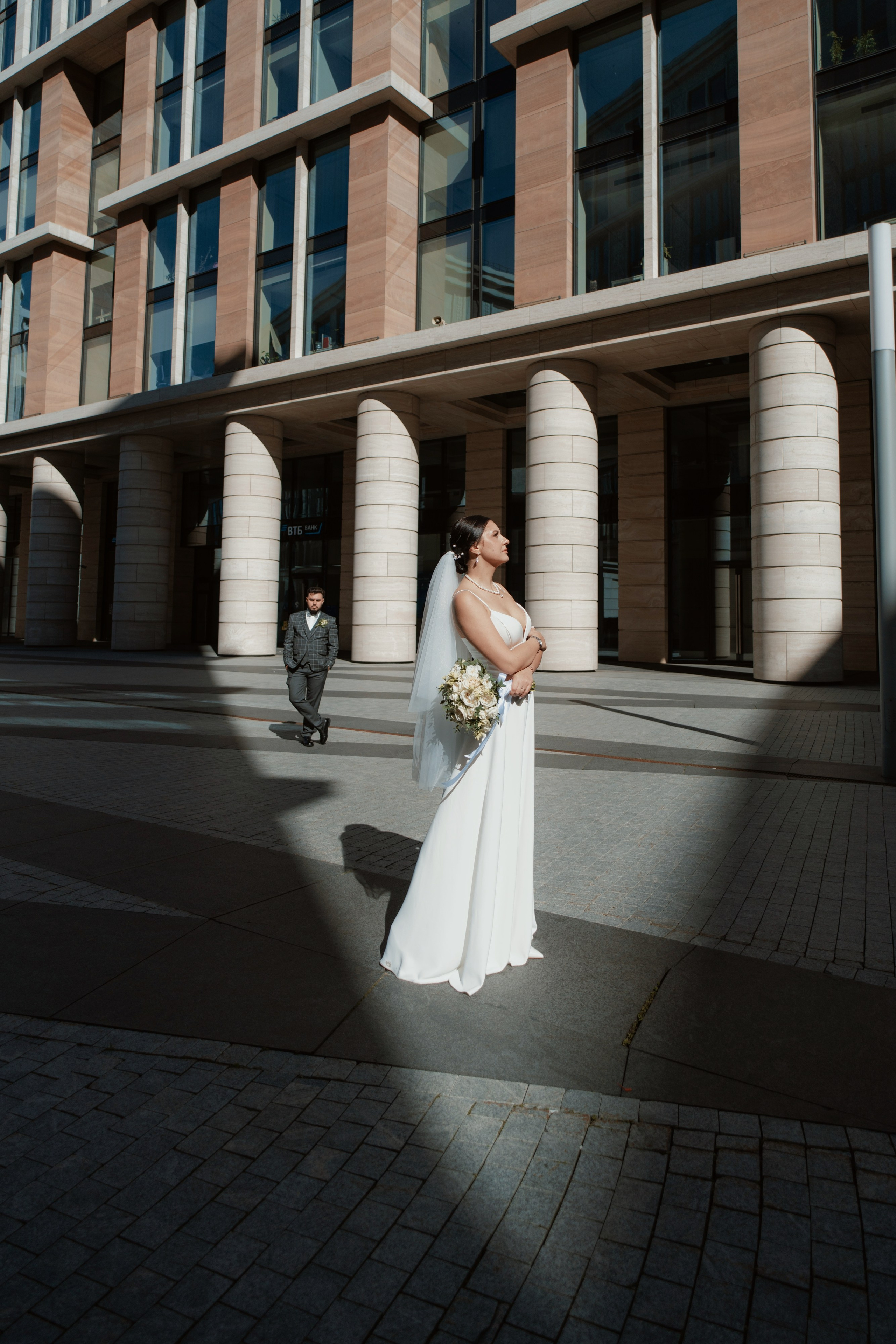 Свадебная фотосессия в Невской ратуше. Невеста на переднем плане в луче солнца.