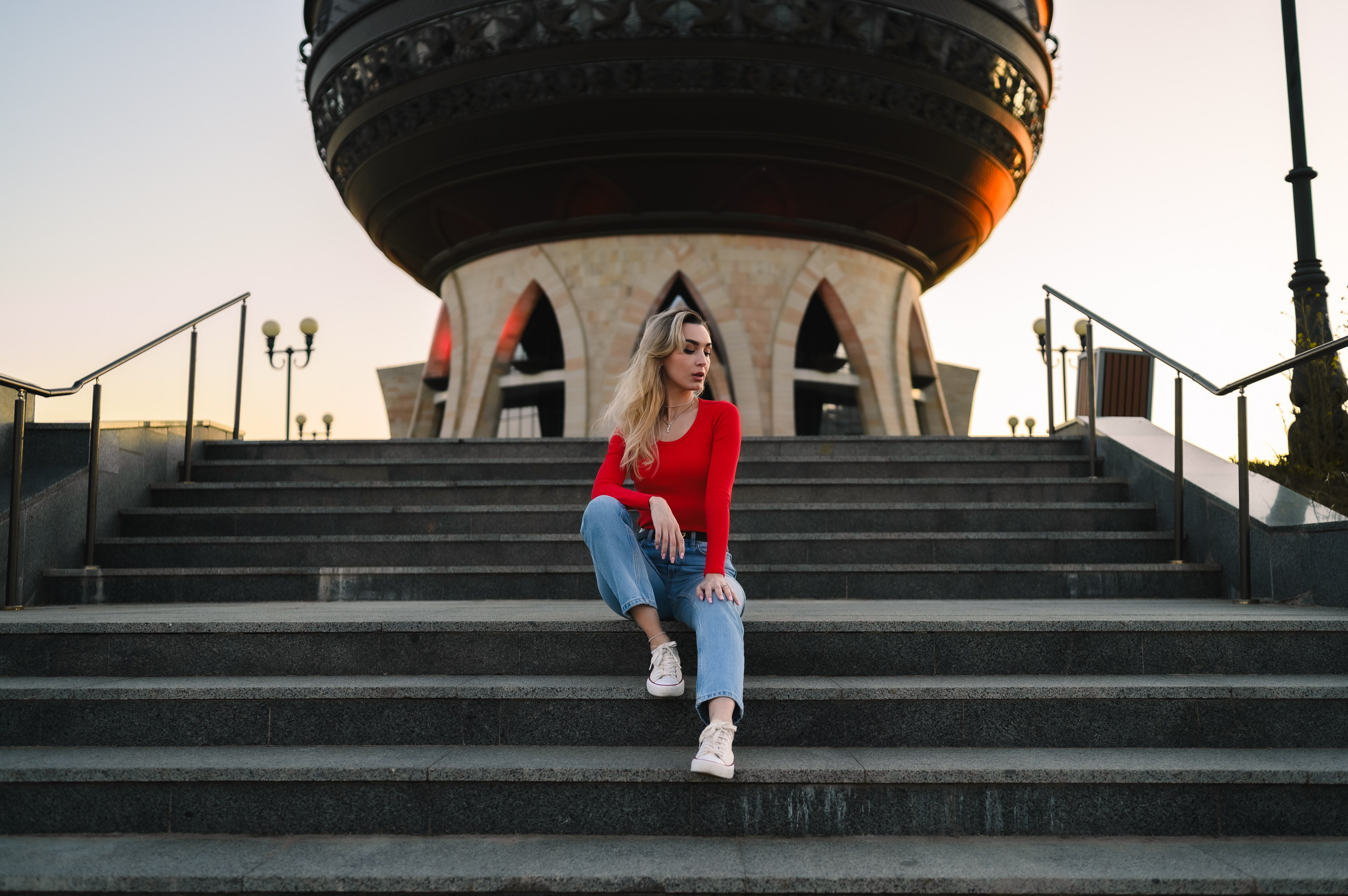 Фото девушки в джинсах и красной кофте у достопримечательности
