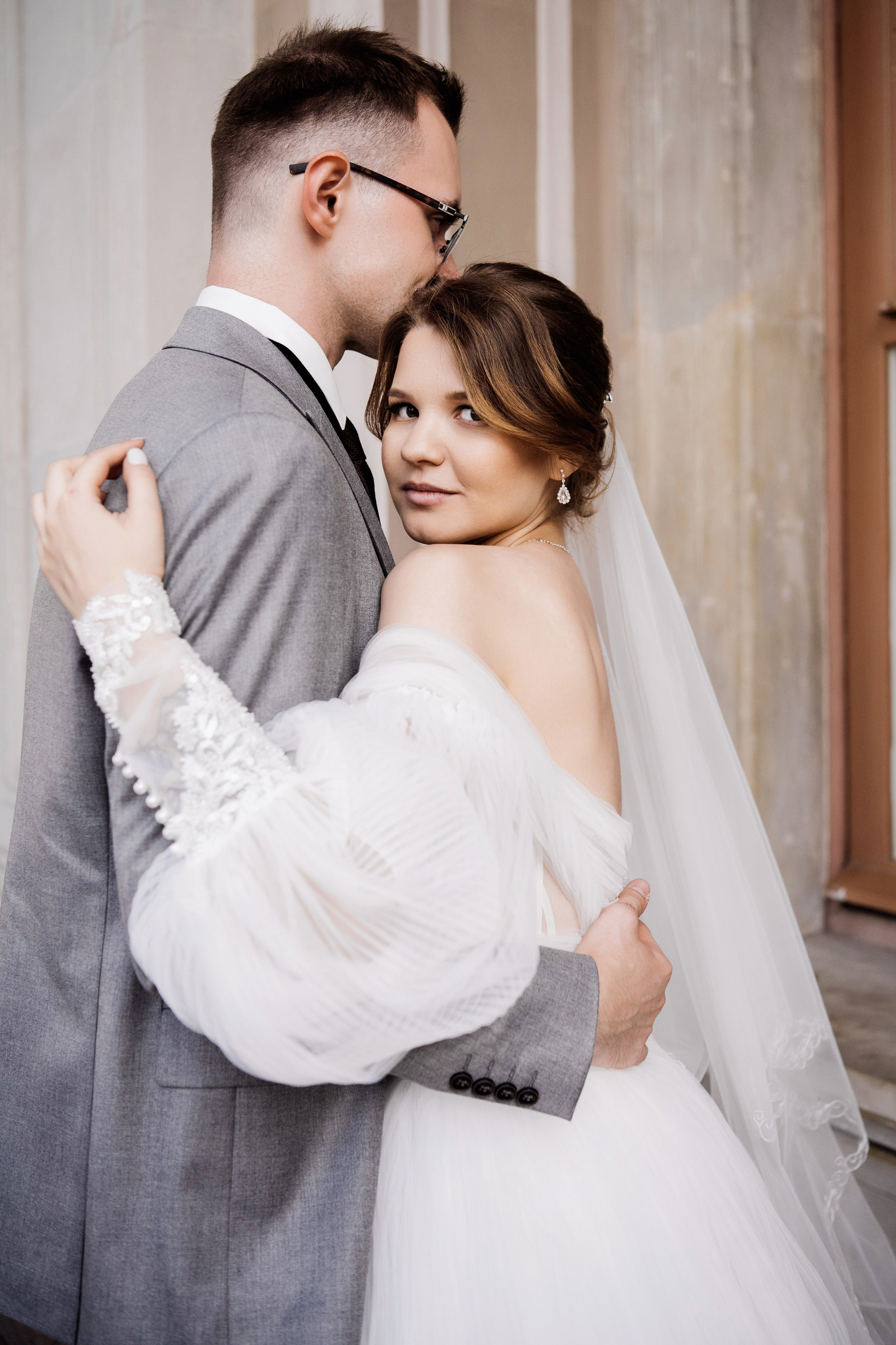 Невеста обнимает жениха у колонны — портрет в классическом стиле