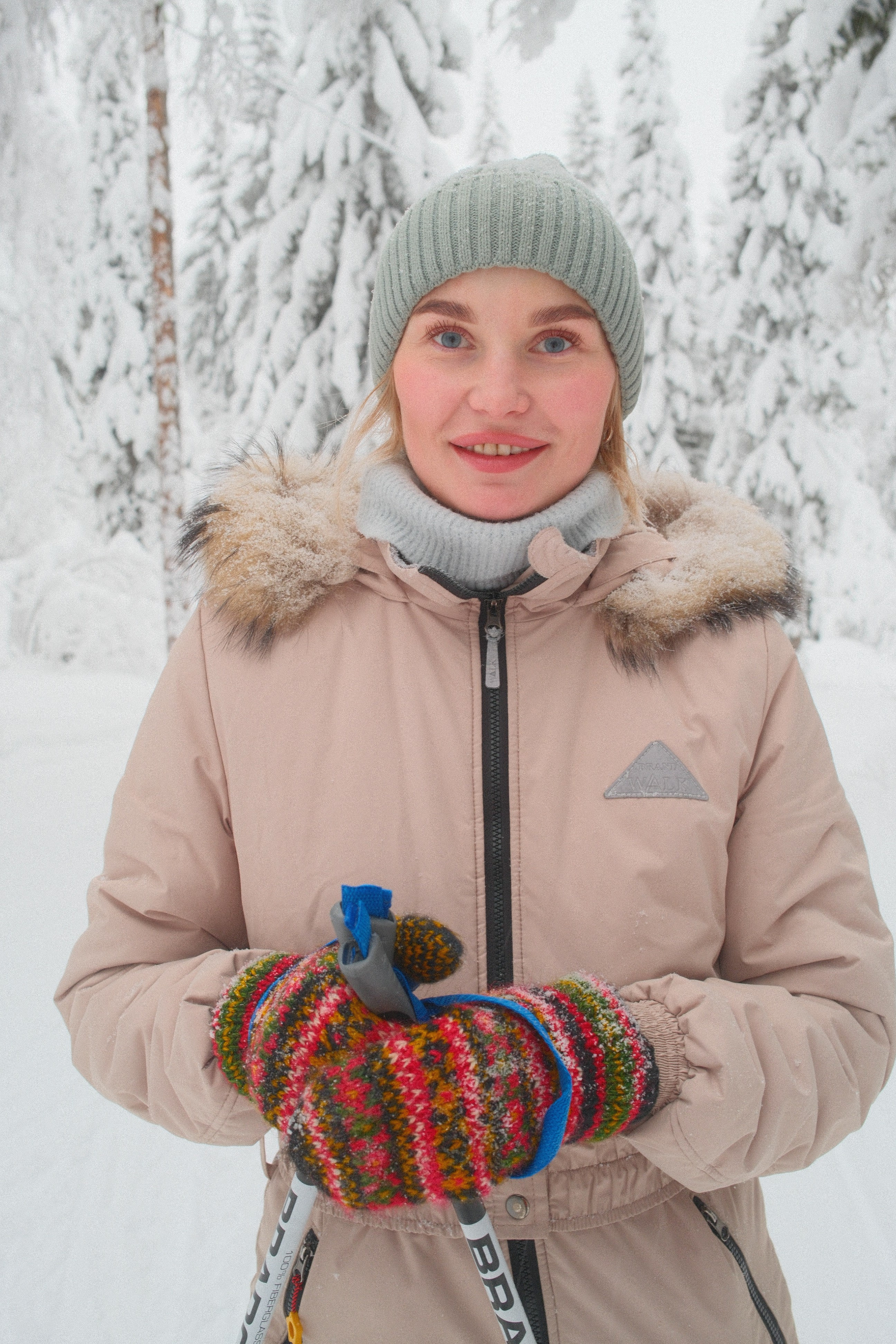 Девушка в бежевом лыжном костюме на лыжах в заснеженном зимнем лесу