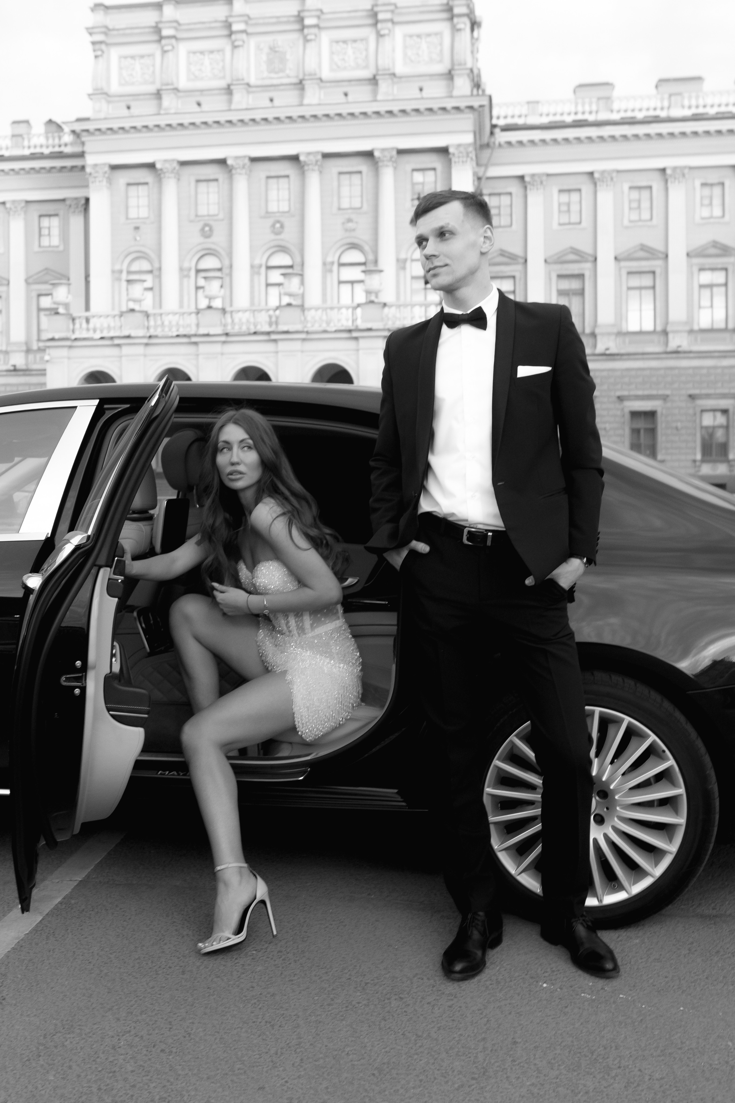 Девушка выходит из дорогой машины, рядом стоит жених