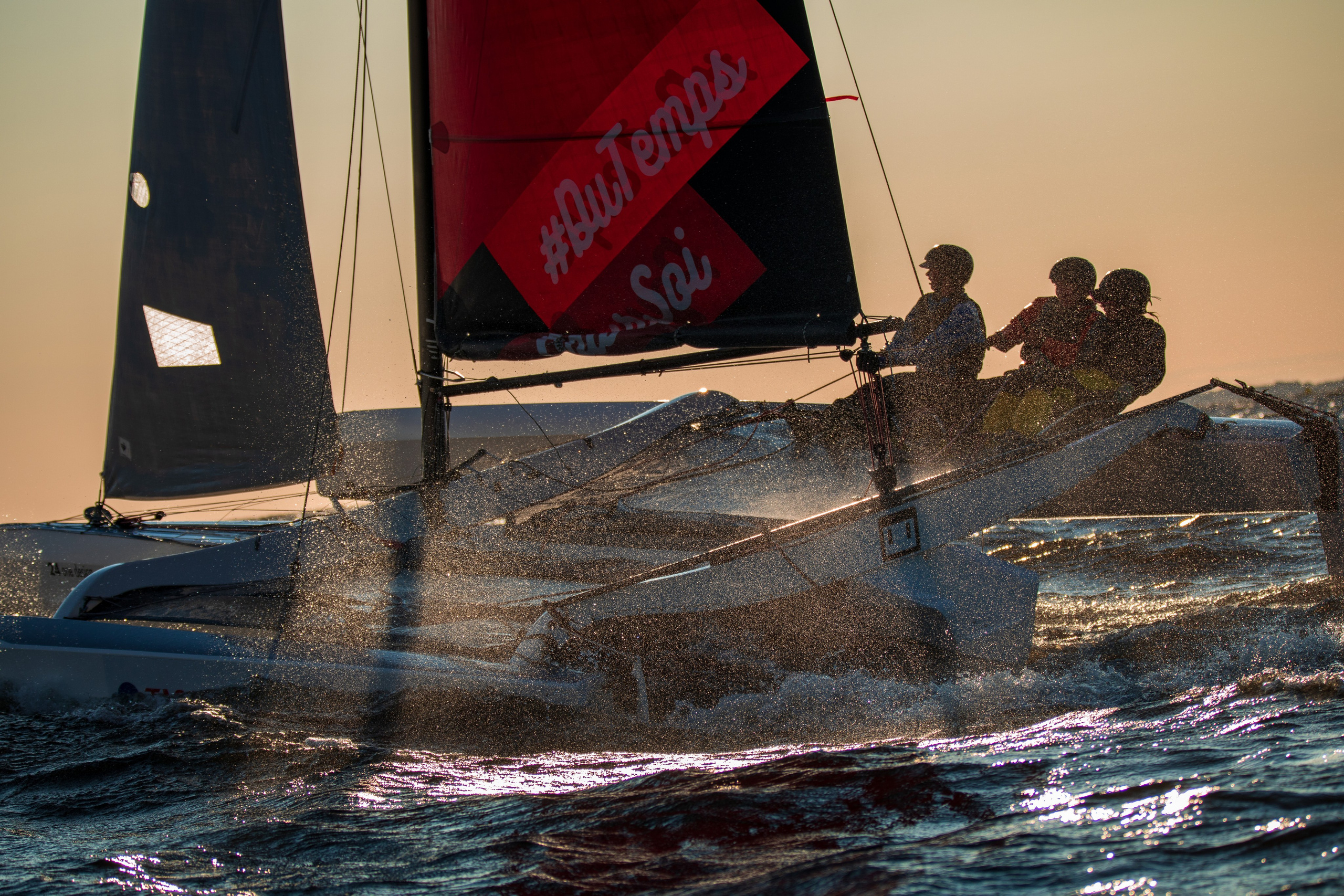 Тень от яхты на брызгах в контровом свете. Гонки  тримаранов. 