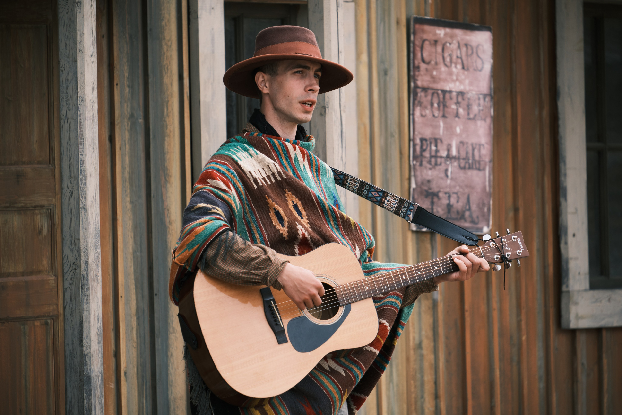 Мужчина играет на гитаре одетый в пончо