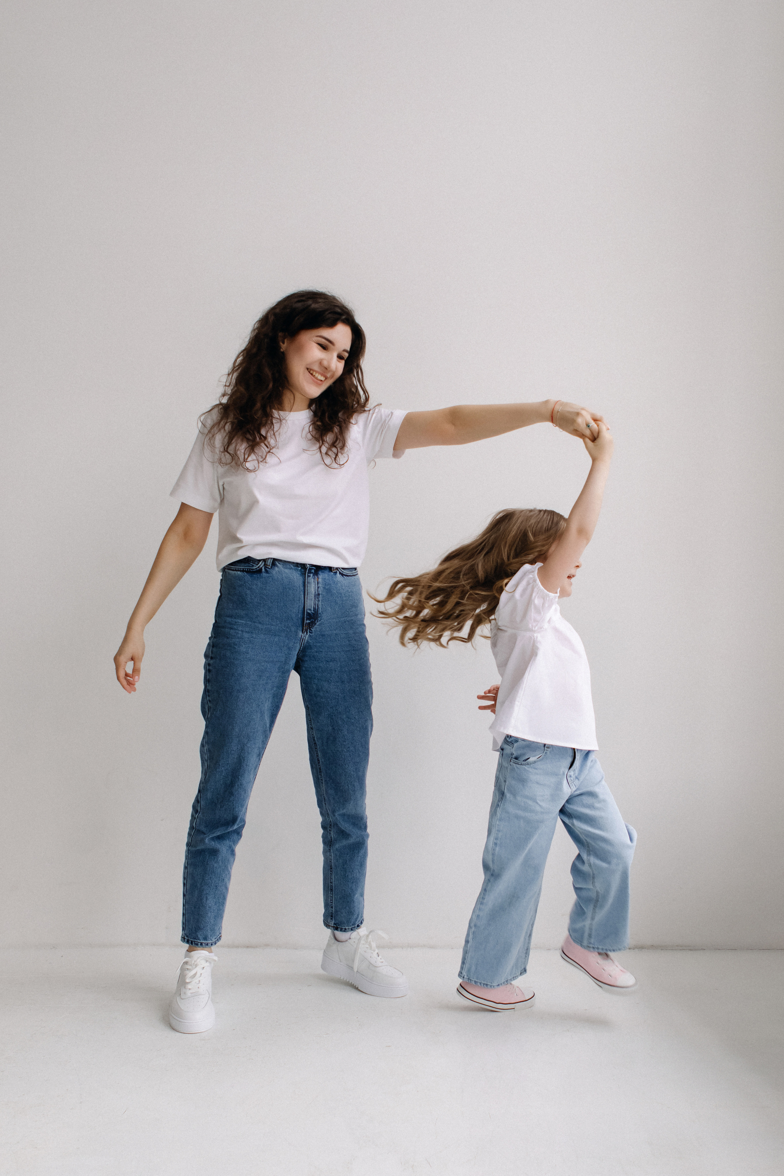 Мама и дочь в джинсах и белых футболках танцуют