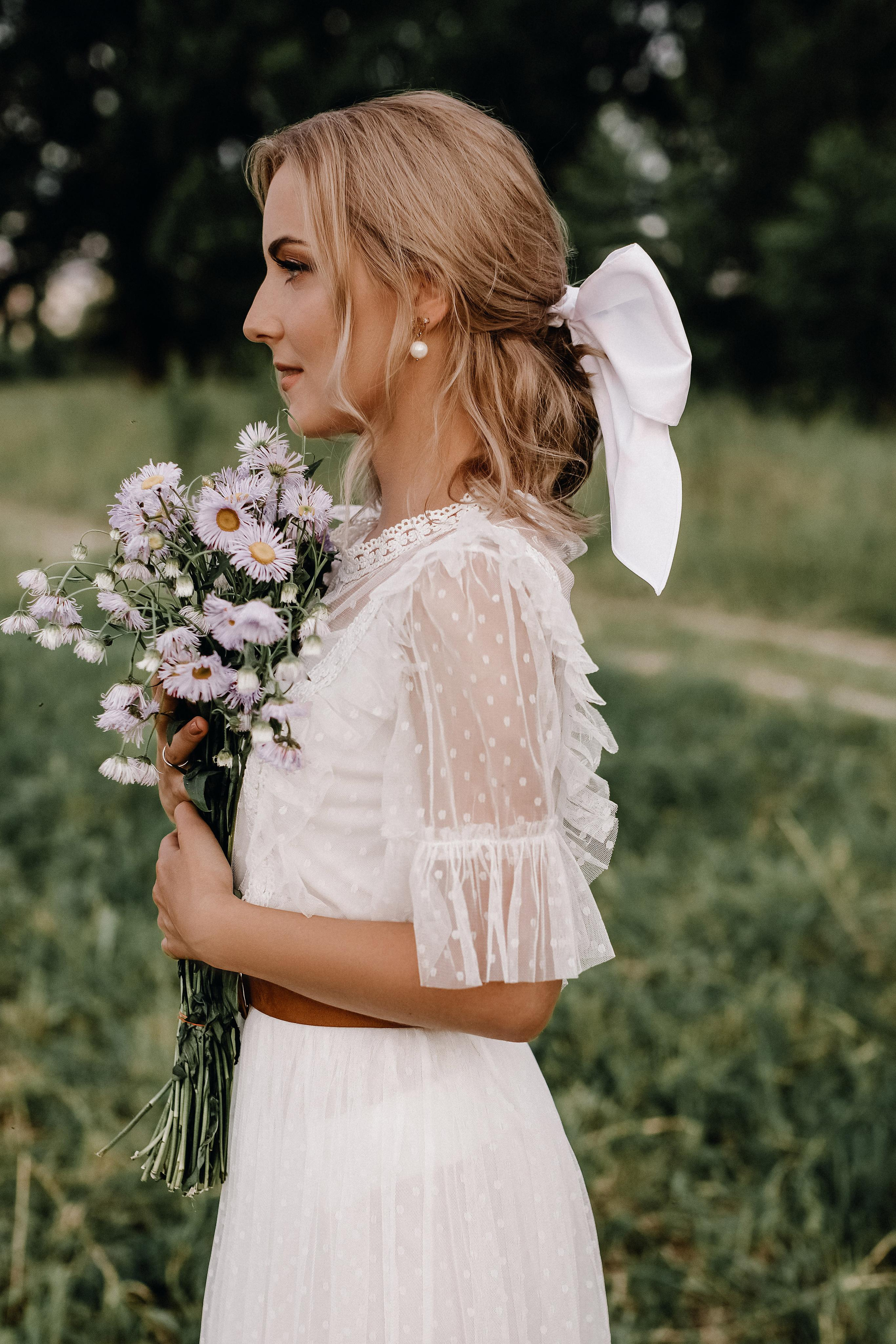 Невеста с бантом в волосах и букетом ромашек в руках