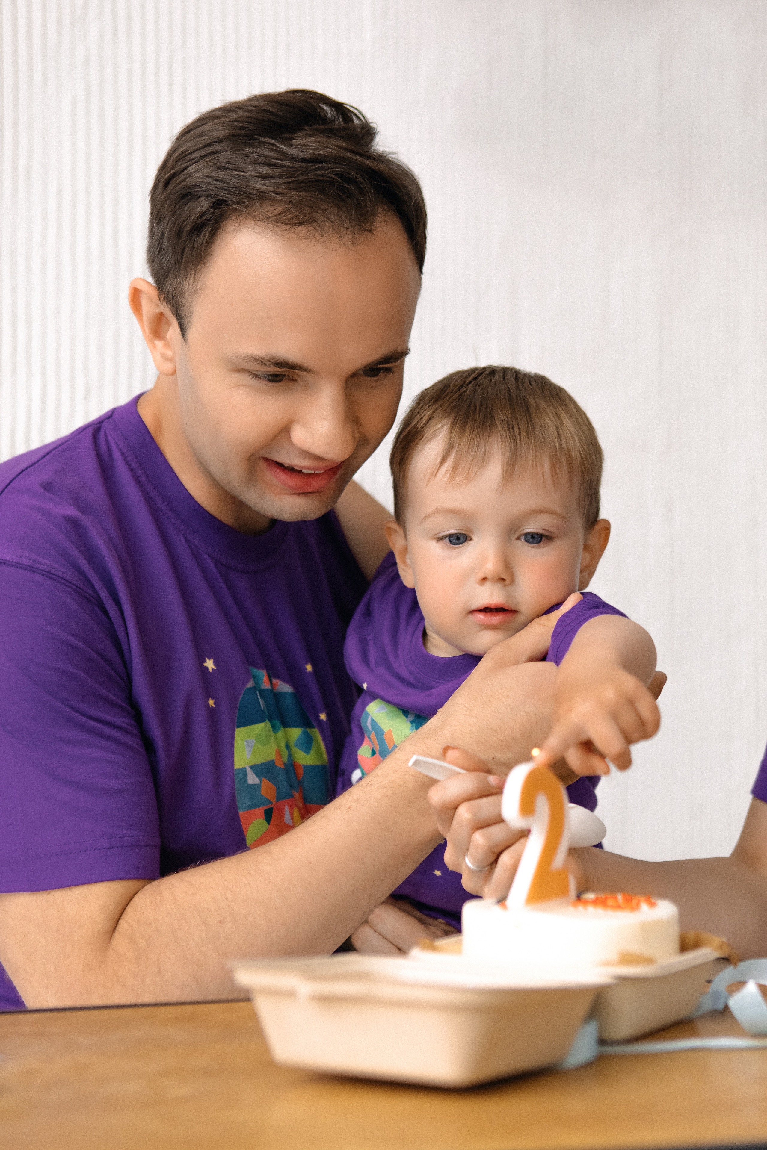 Папа и сын задувают свечи на торте