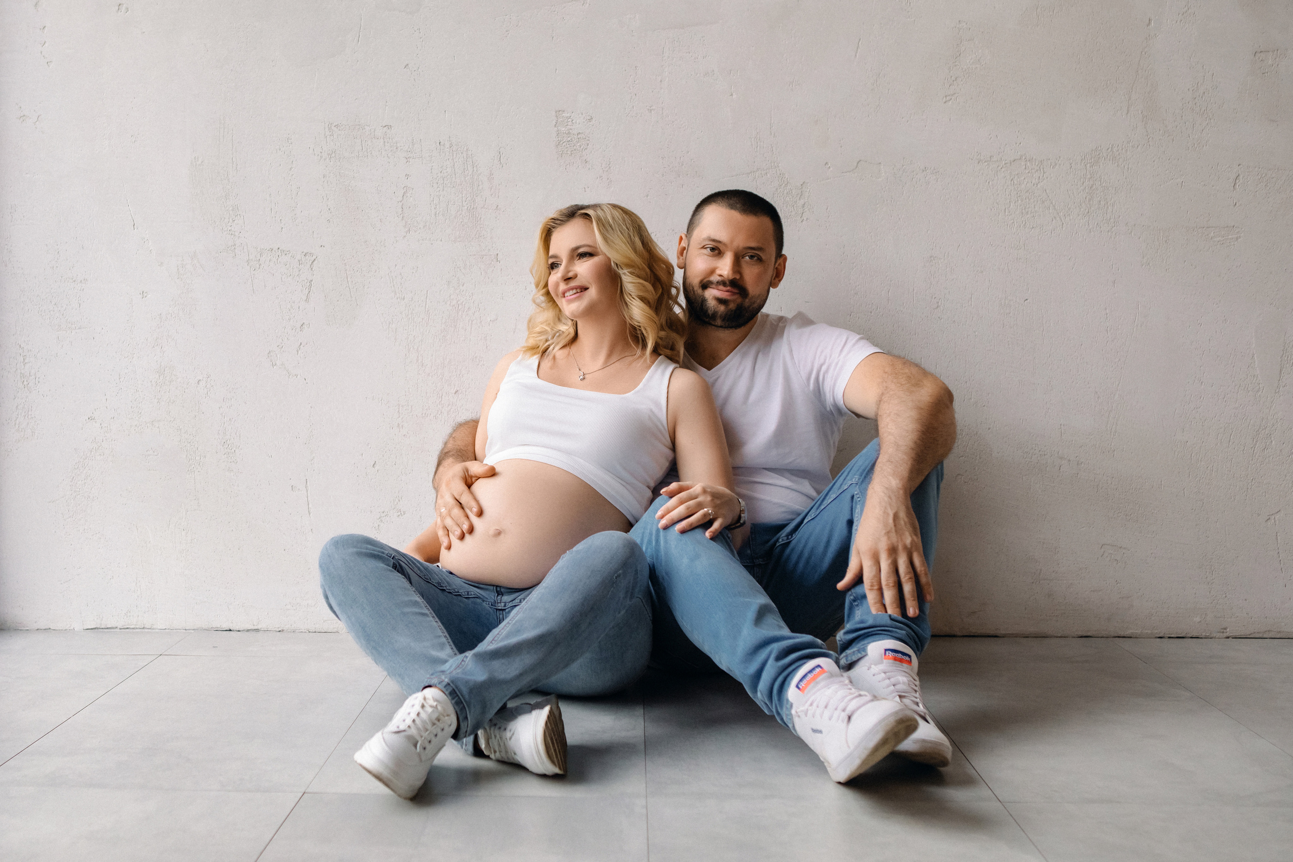 Счастливая пара в ожидании рождения в джинсах и футболках