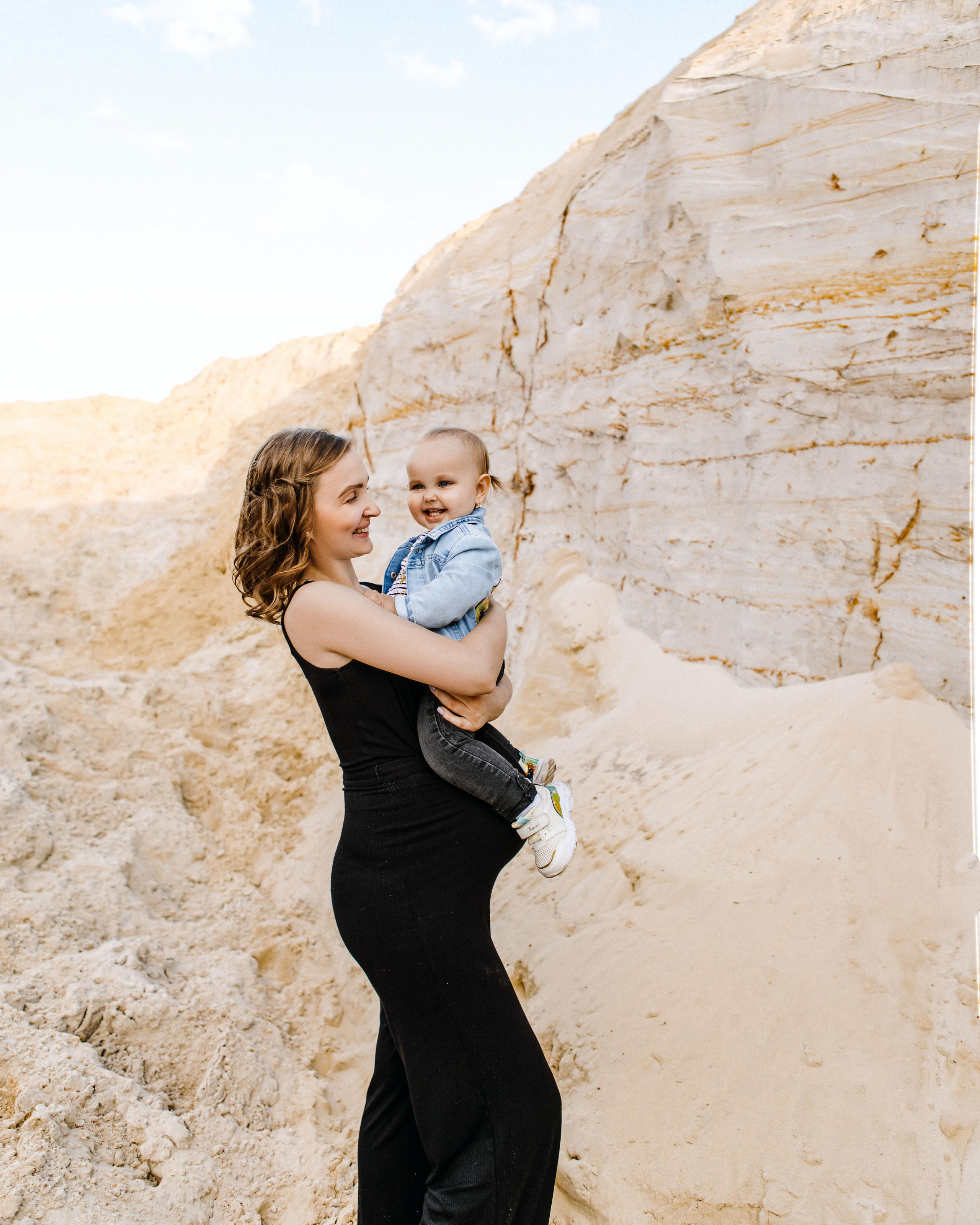 беременная мама держит на руках ребенка в карьере Дзержинский