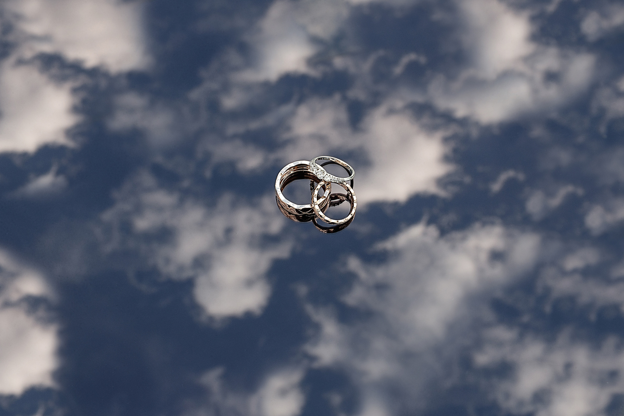 Свадебные кольца креативно сняты на фоне неба. 