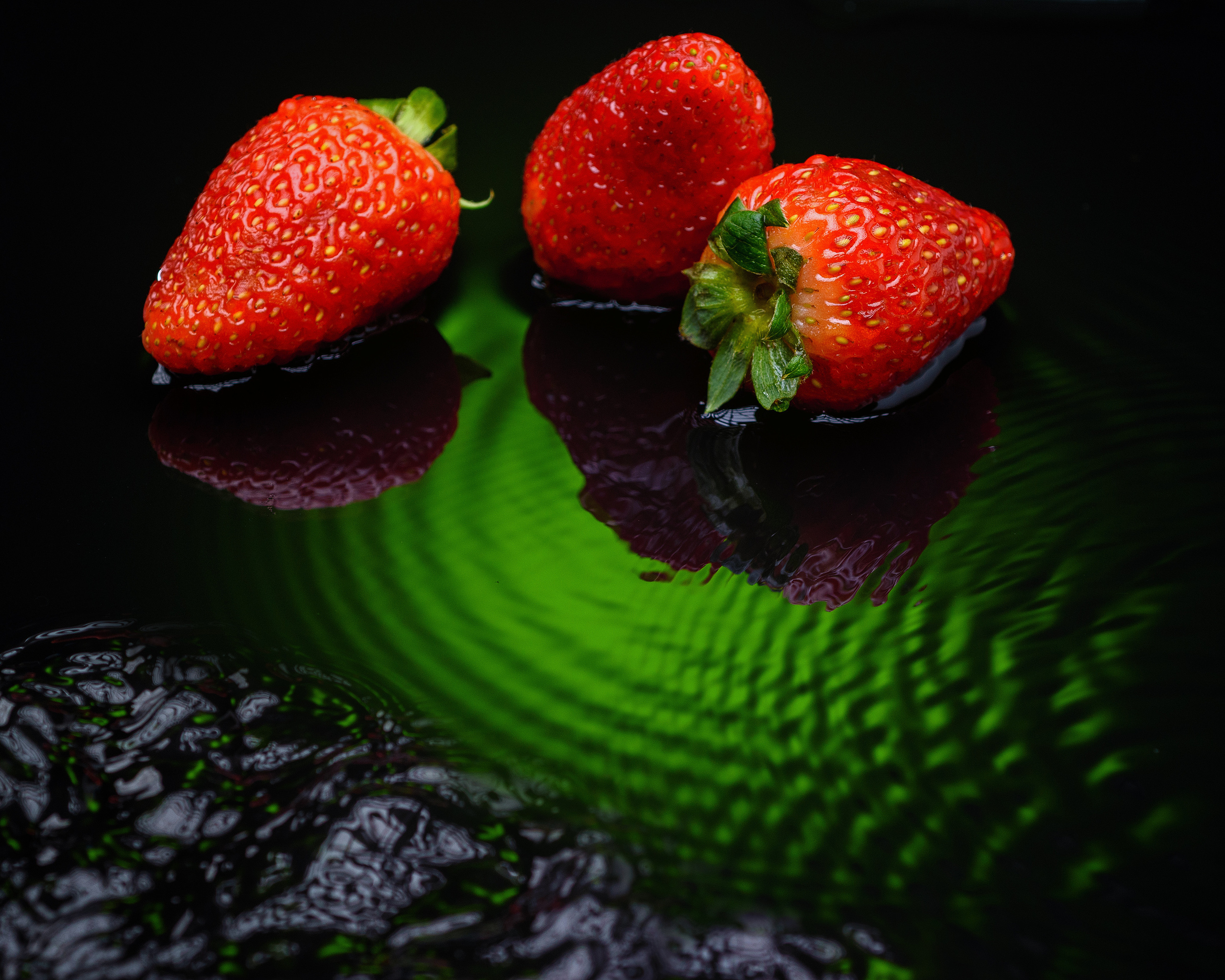 клубника на черном стекле с водным фоном и зеленым светом