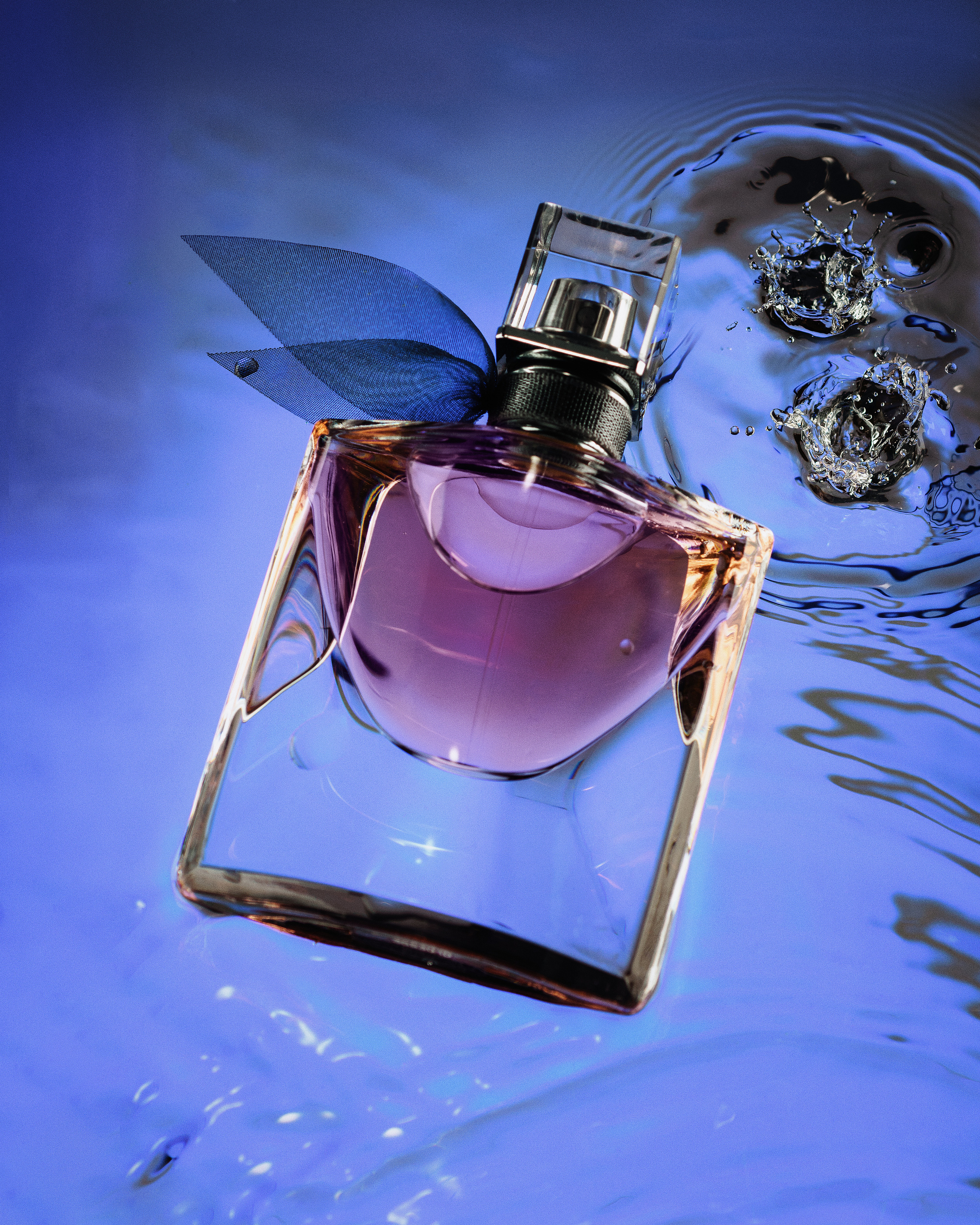 флакон духов Lanсome в воде с каплями воды