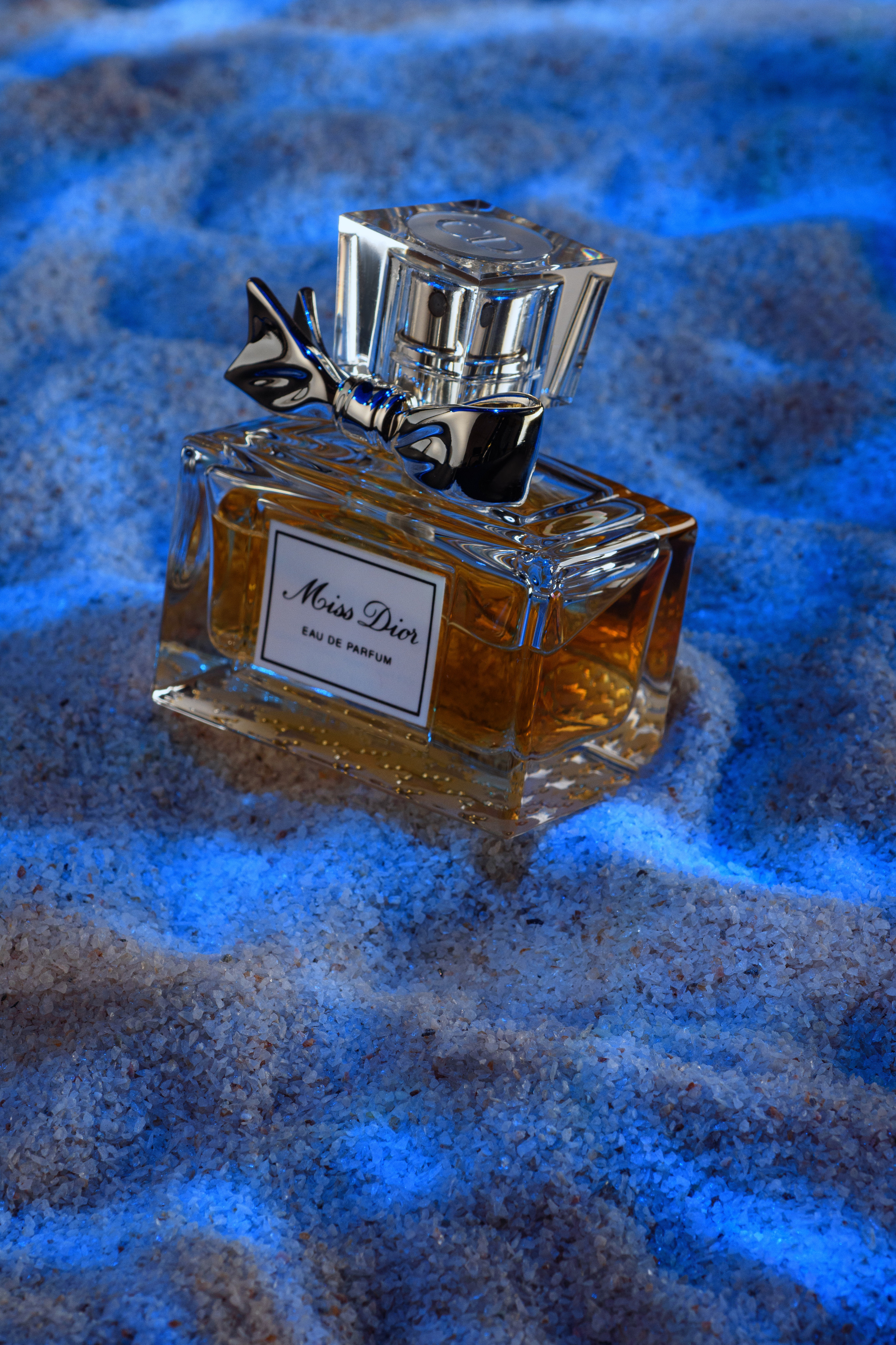 флакон духов Miss Dior на морском дне и солнечными отражениями
