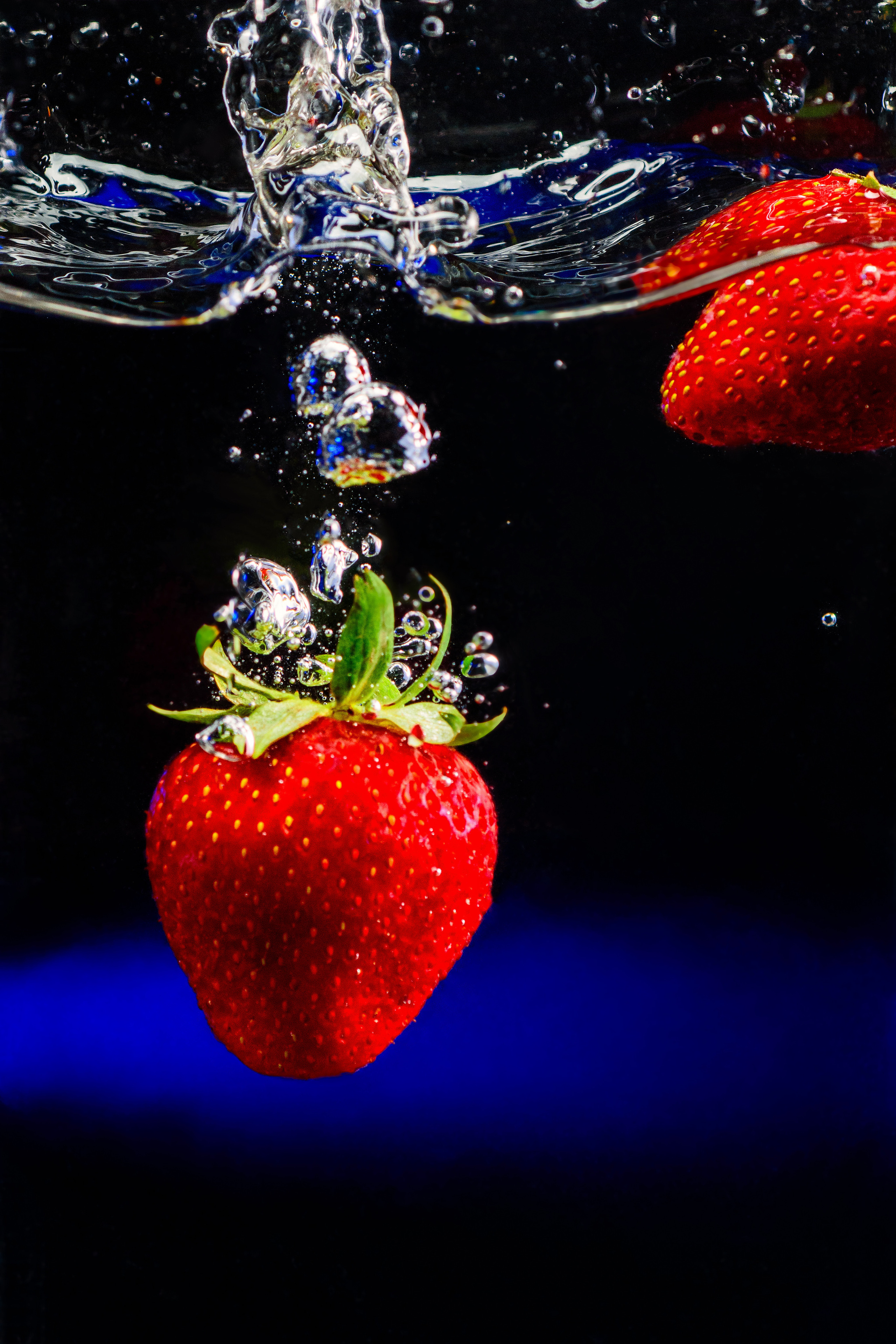 клубничный сплеш на черном фоне с синим светом