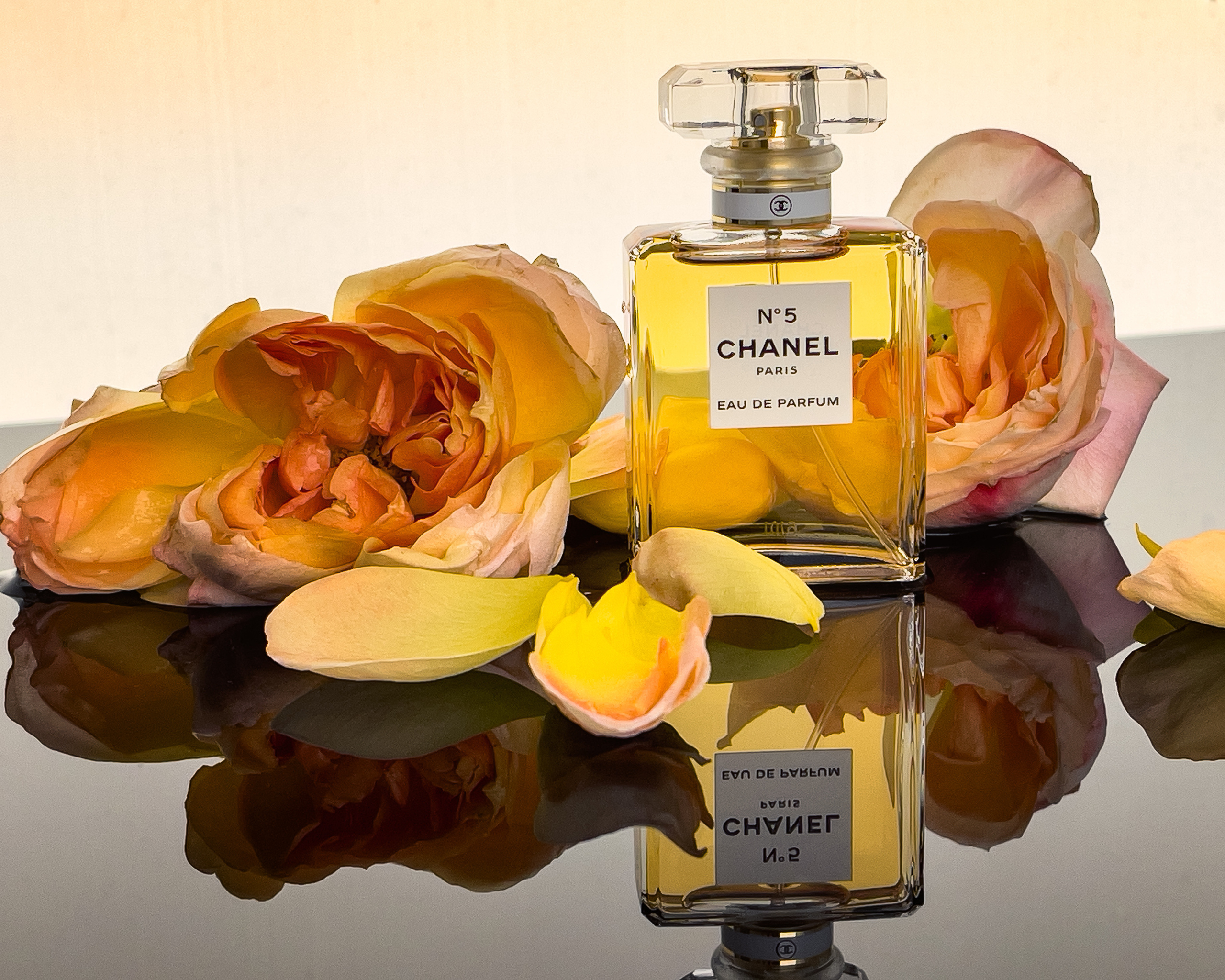 флакон духов Chanel N° 5 с цветами пионовидной розы с отражениями
