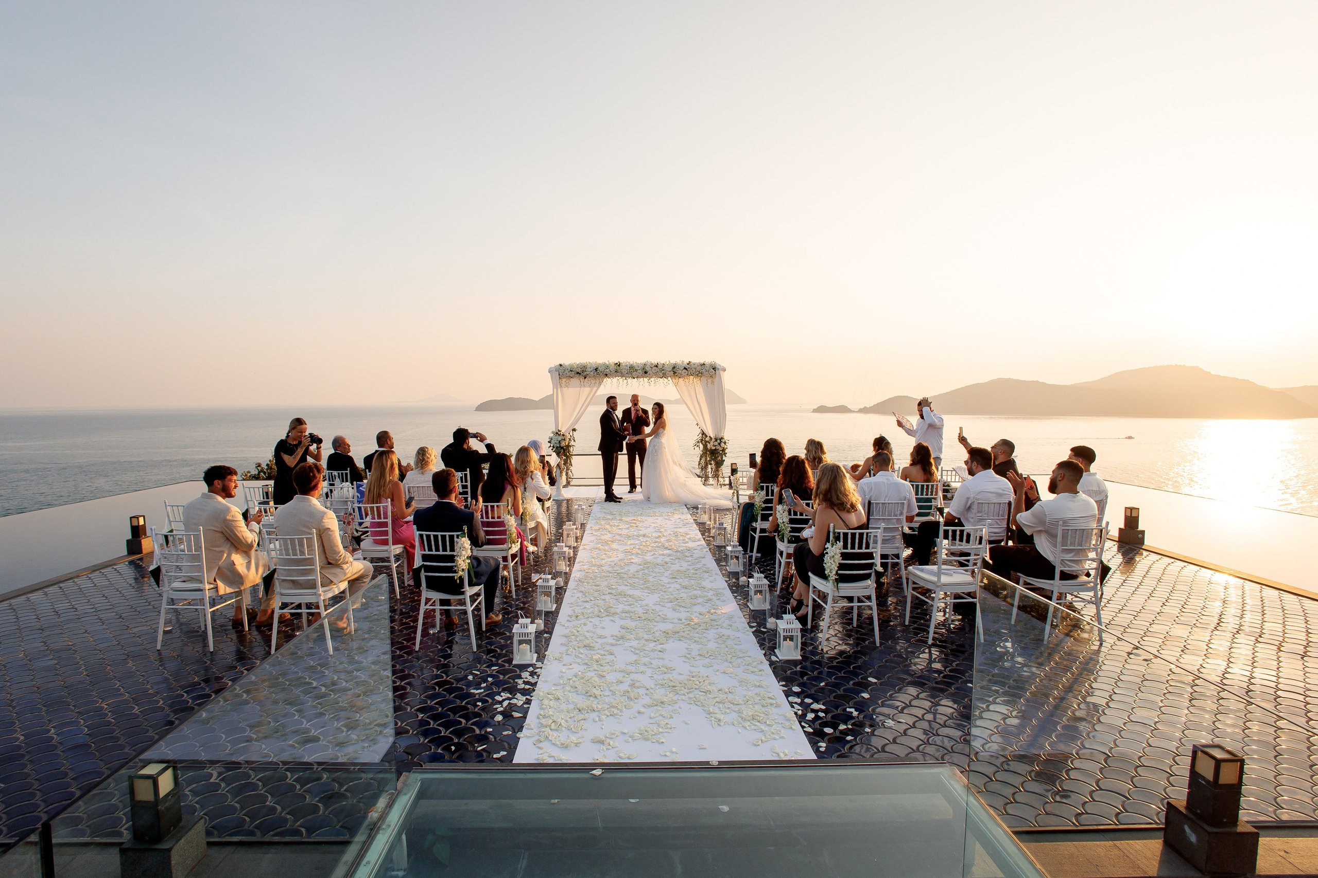гости аплодируют жениху и невесте с шикарным видом на андаманское море