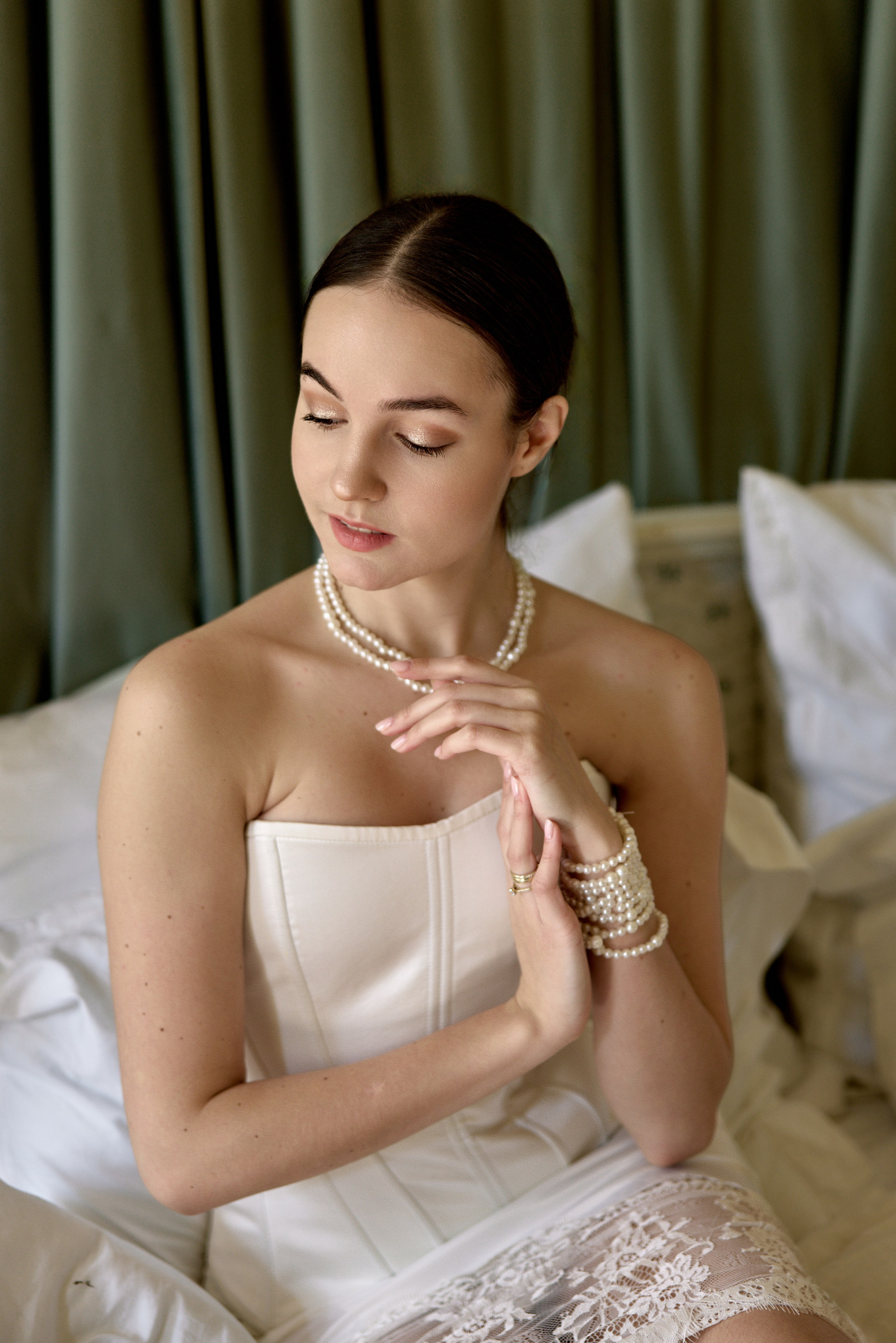 "Крупный план девушки в постели — мягкий утренний свет падает на лицо, расслабленная поза, легкая улыбка, оголенное плечо прикрыто простыней."