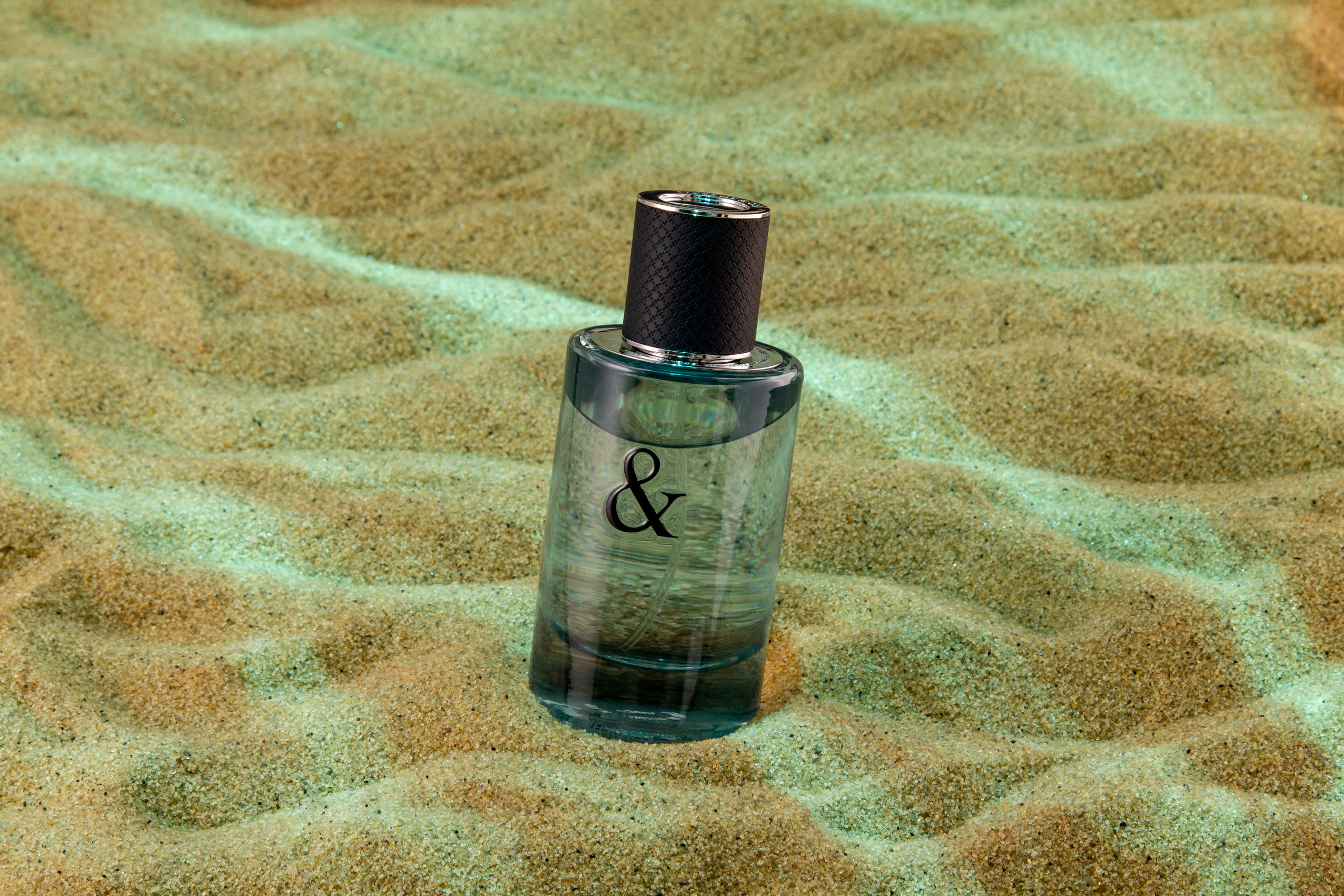 Парфюм на песчаном морском дне в бликах утреннего солнца.