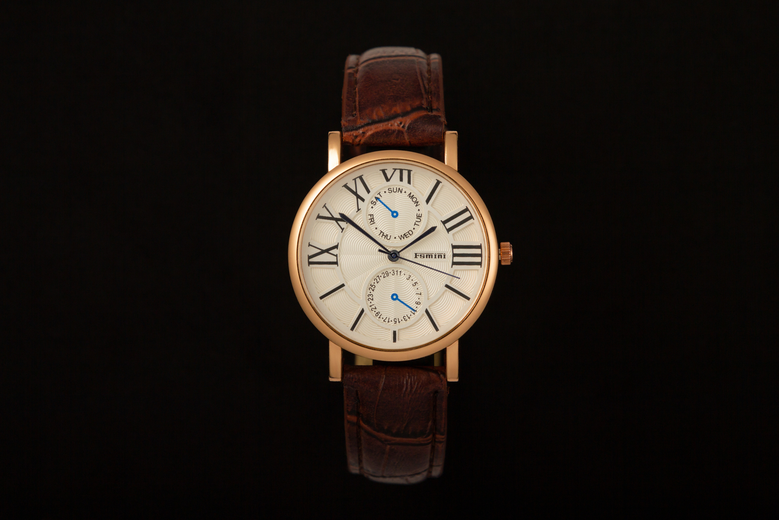 Золотые часы с кожаным ремешком на чёрном фоне