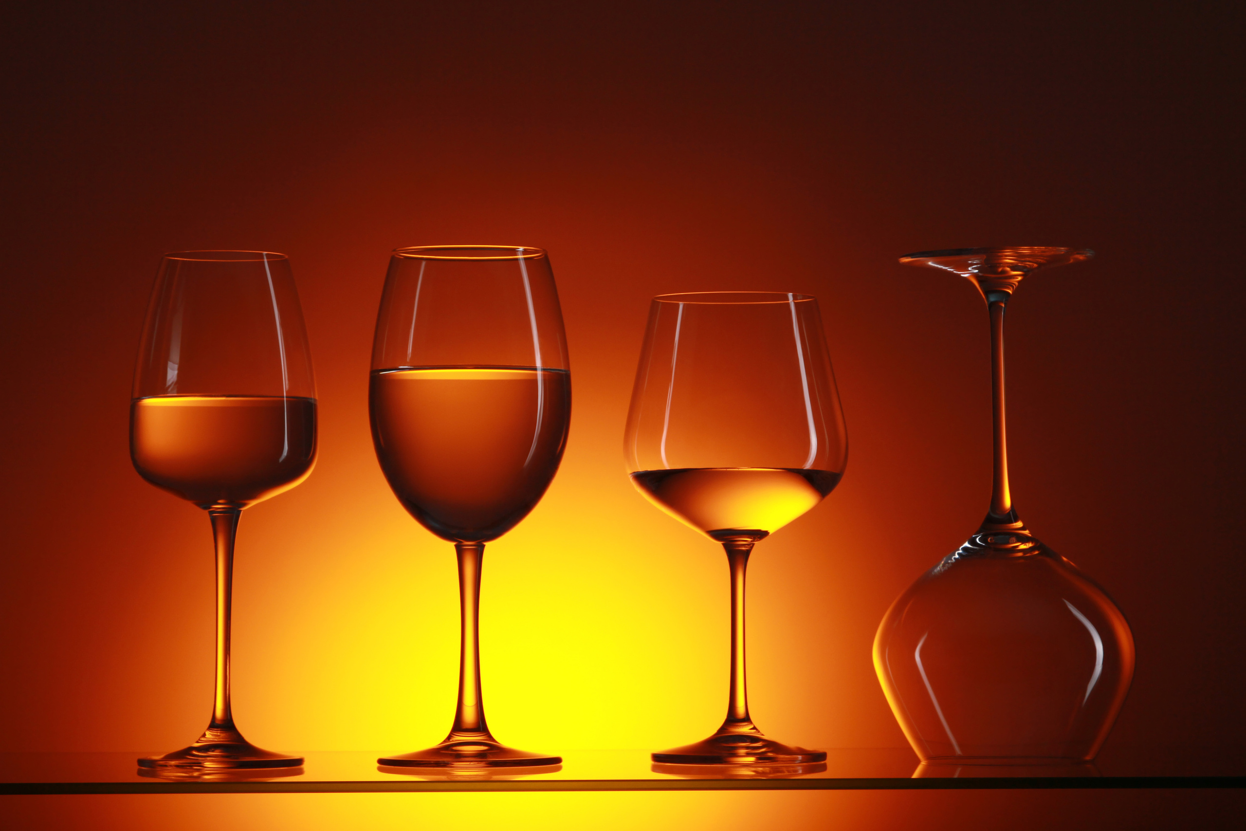 Стеклянные бокалы под разное вино на фоне заката. Удивительный ракурс. 