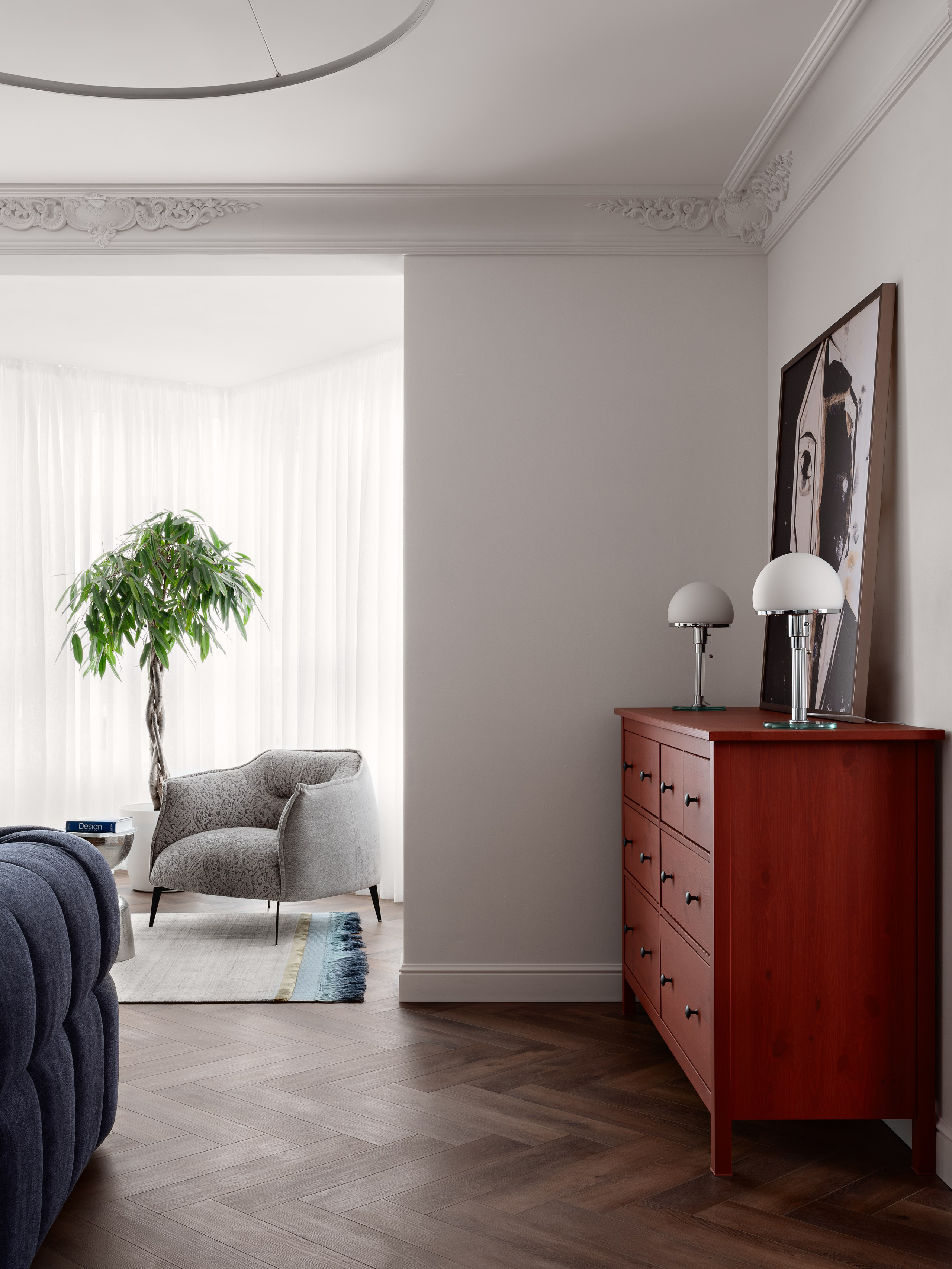 Интерьер гостиной в современном стиле: фото с акцентным красным комодом, настольными лампами в ретро-стиле, мягким диваном и уютным креслом у окна. Проект реализован дизайнером Антоном Логиновым, стилистическая работа — Алёны Мощенской, фотография Сергея Денисенко.